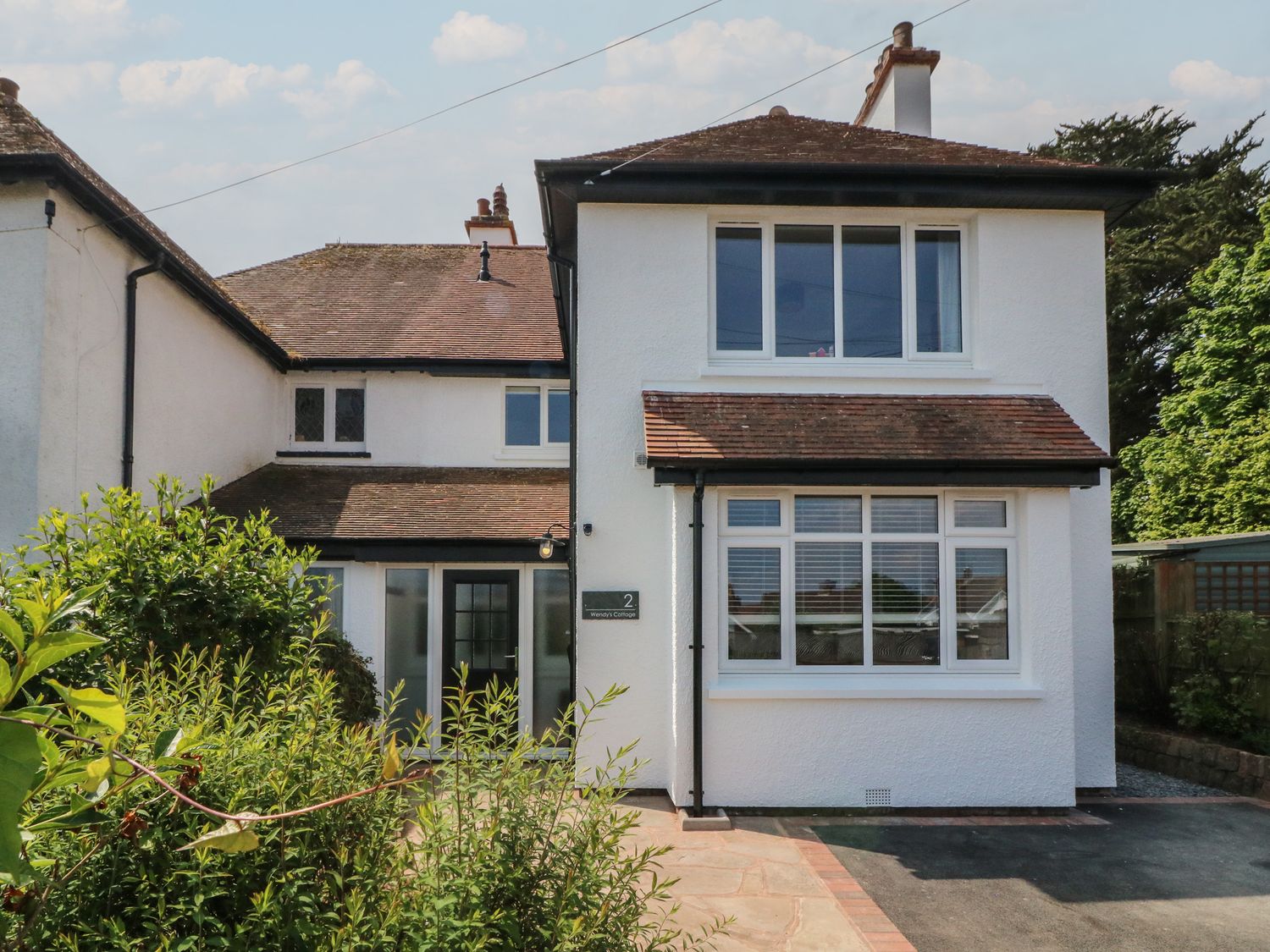 A two story white house with multiple windows and a front garden at Wendys Cottage in Minehead