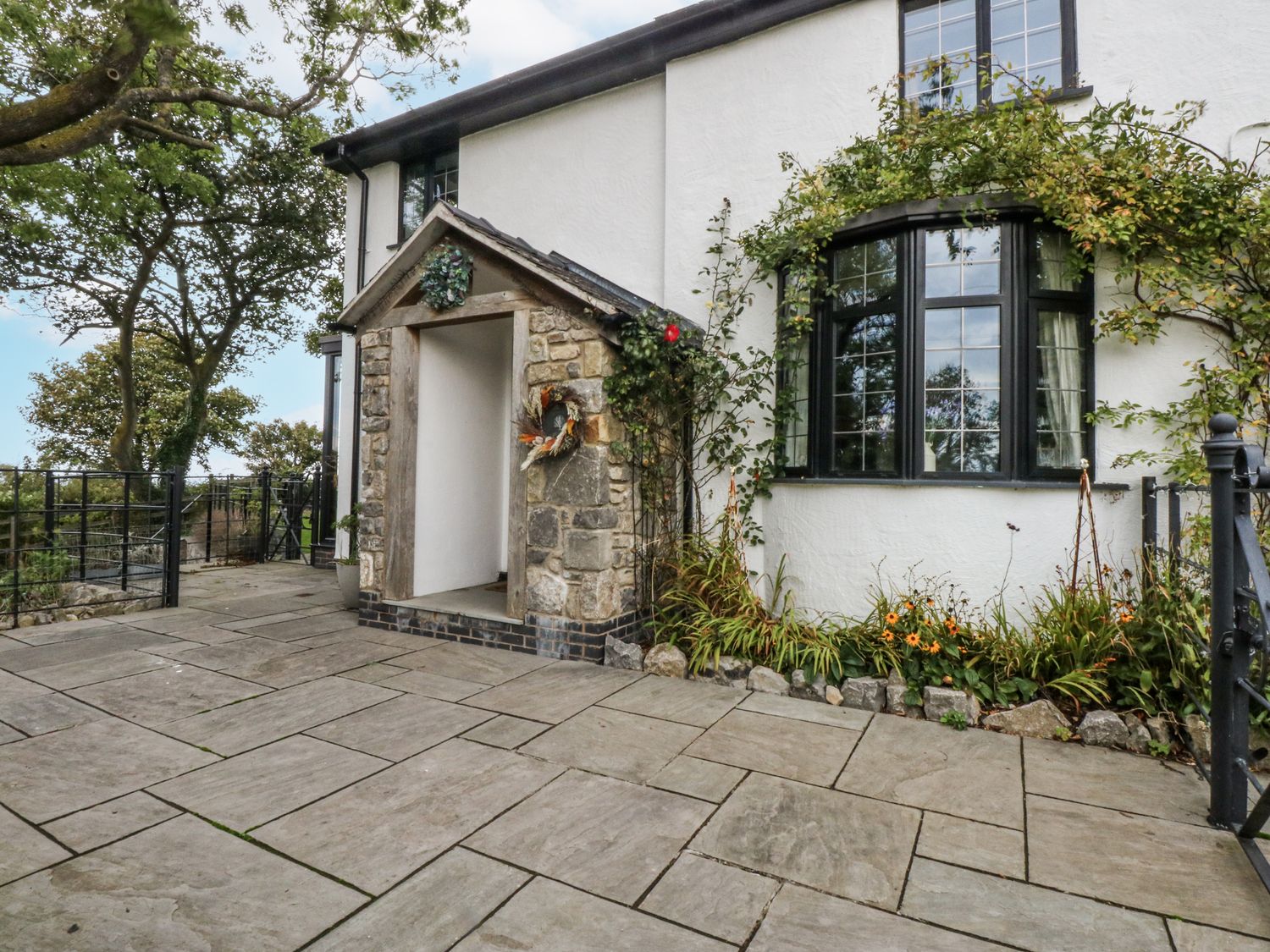 An outdoor entrance with stone pathway and flower arrangement at Windyridge in Gwaenysgor, near Prestatyn
