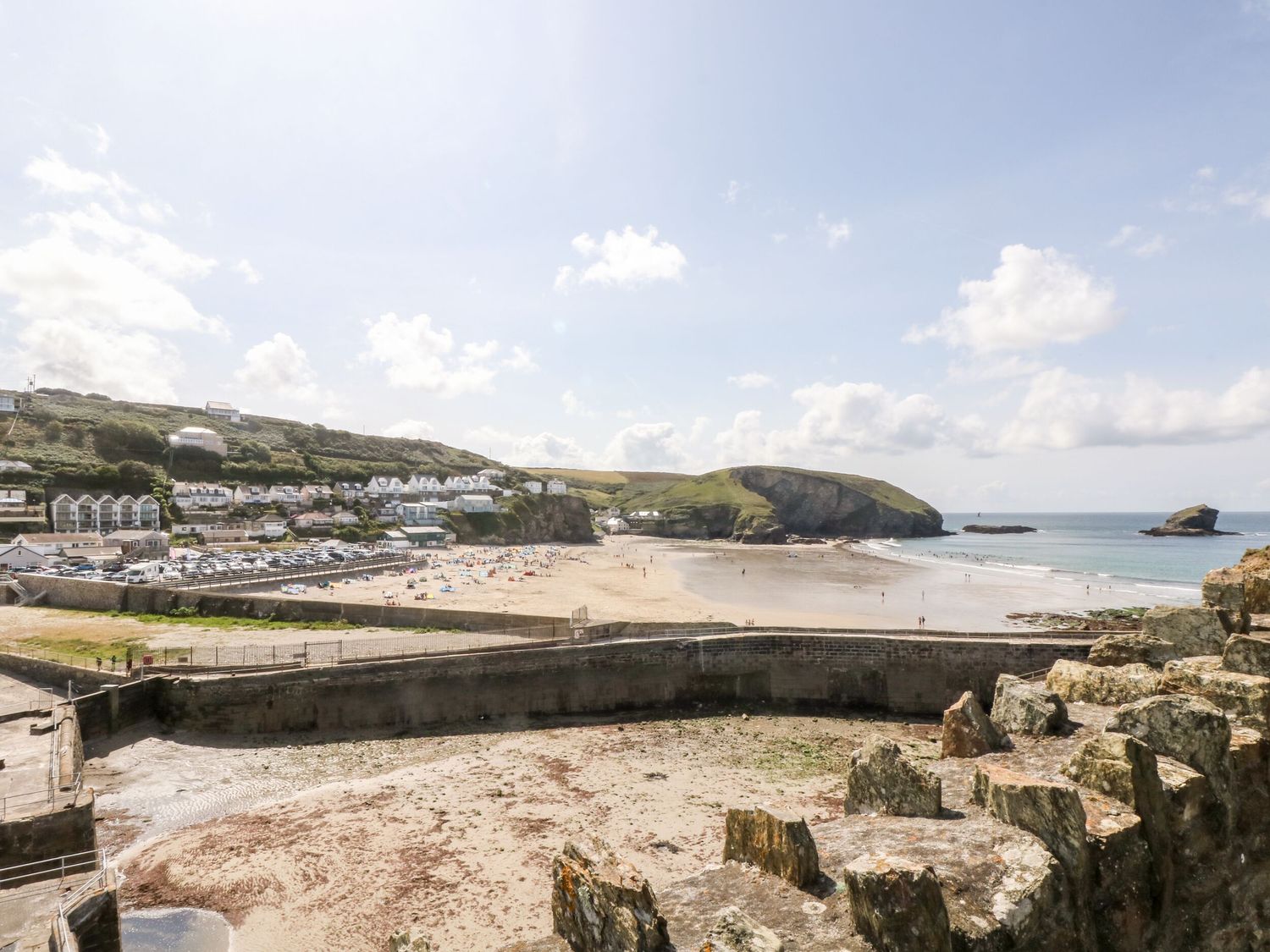 A beach with sand and a rocky shoreline with houses on hills and a sea view at Scarboro in Redruth