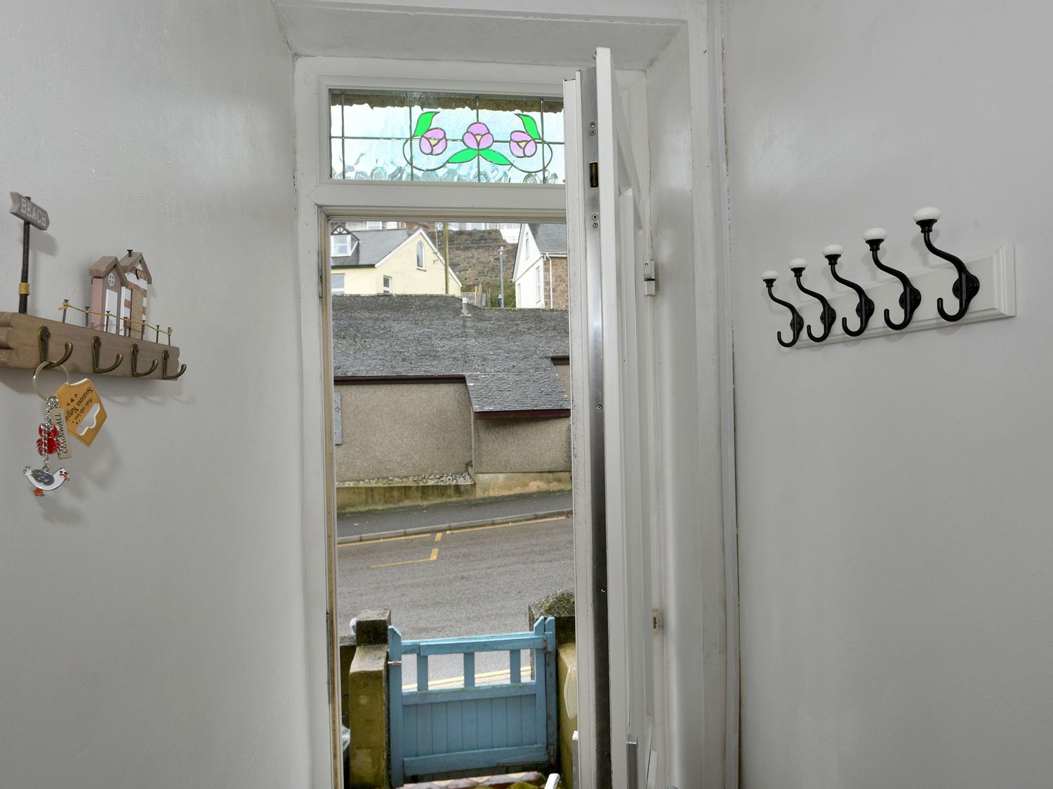 A hallway with a door open to a street a blue gate outside and coat hooks on the walls at 5 St Ives in St Ives
