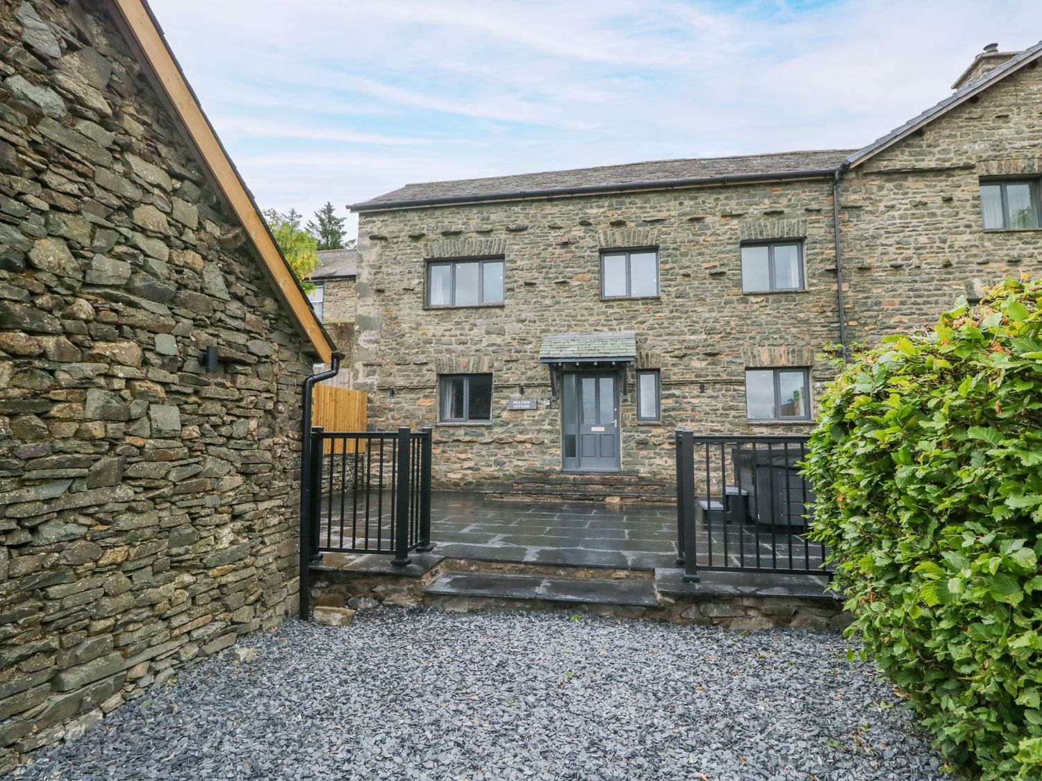 An exterior view of a house with stone walls and a fenced entrance at Fell View Cottage Lambrigg near Kendal