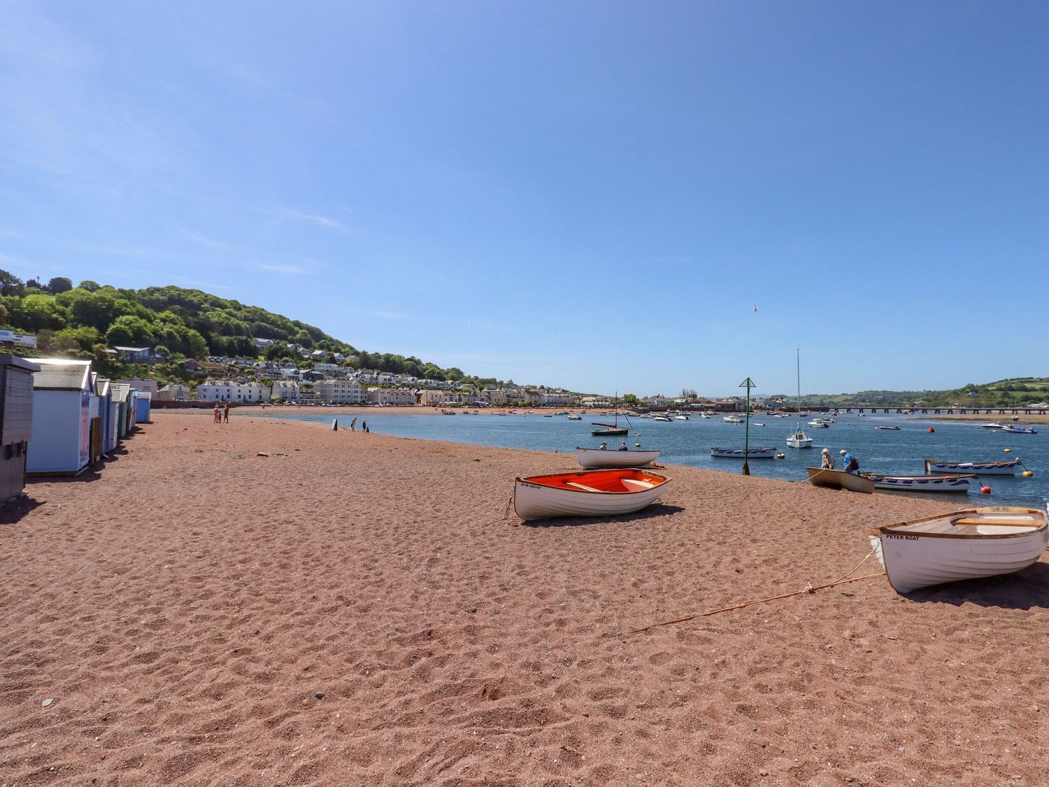 A beach with boats on the sand and in the water with houses and hills in the background at Sanctuary Cottage in Shaldon