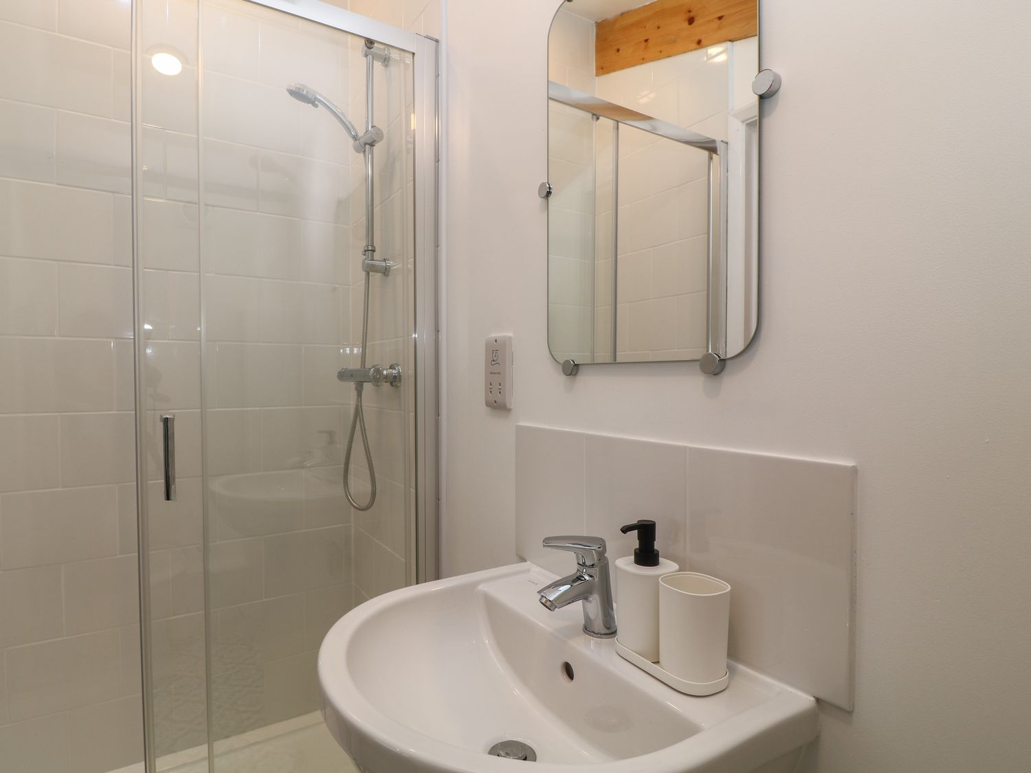 A bathroom with a sink and a mirror next to a shower enclosure at The Cook House in Erlestoke near Great Cheverell