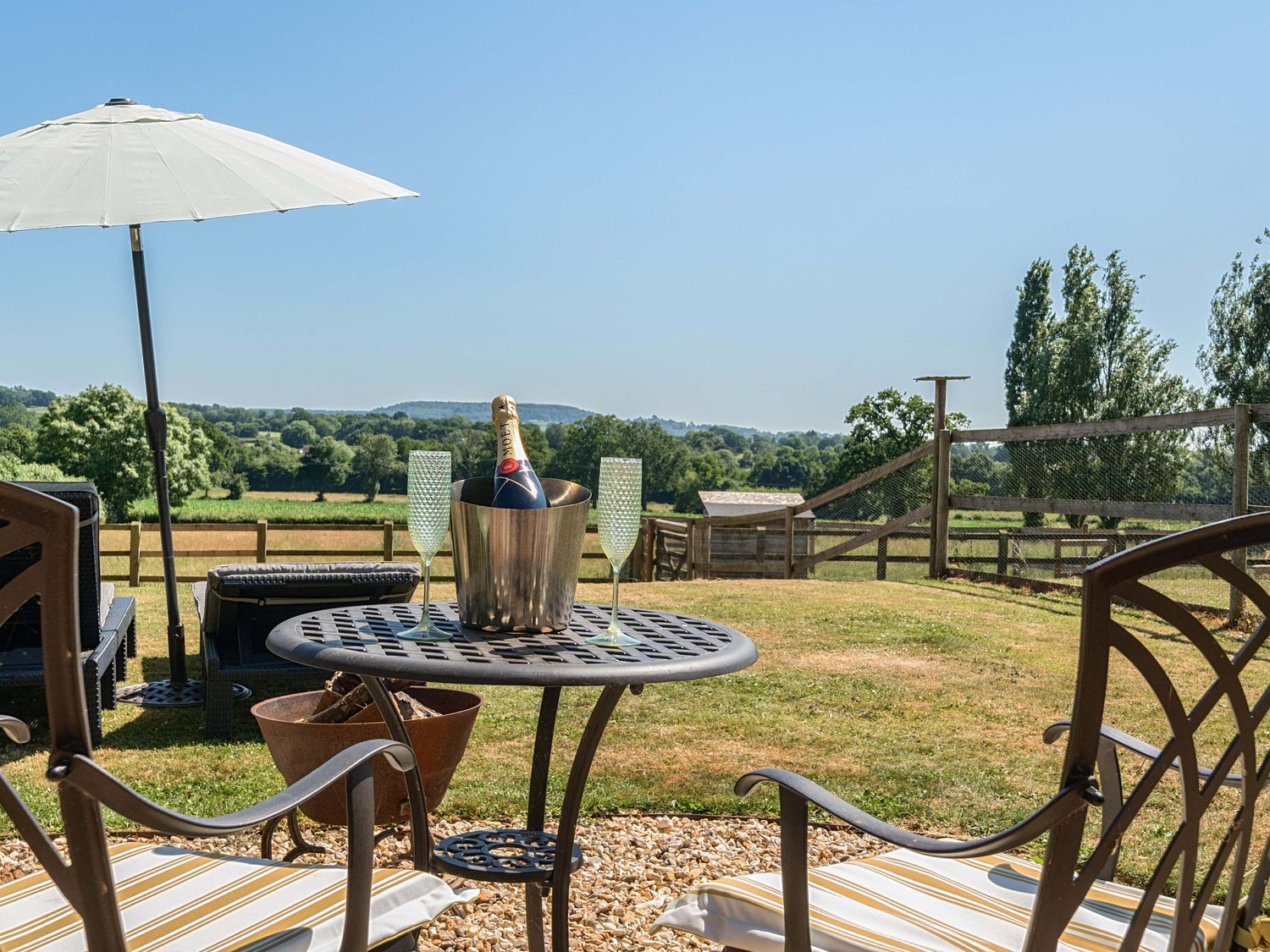 A garden with a table, chairs, and champagne at Piglet Corner in Culmstock