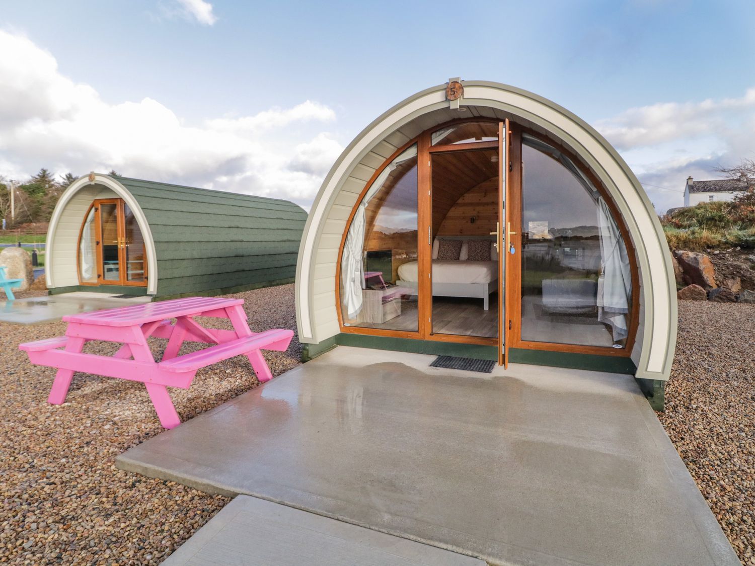 Two pod cabins with glass doors on gravel with a pink picnic table outside at The Wheelhouse Pod No 5 in Burtonport County Donegal