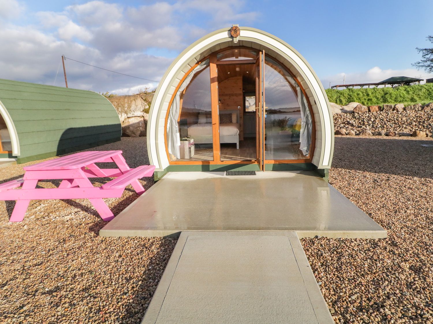 An arched cabin with glass doors and a pink picnic table outside at The Wheelhouse Pod No 8 in Burtonport County Donegal