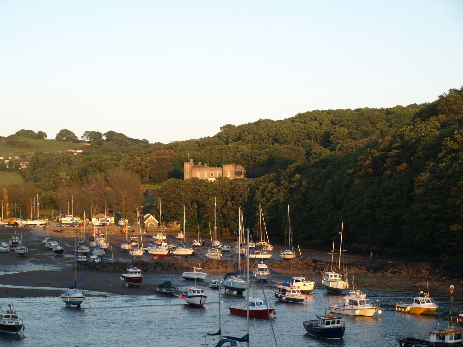 View of boats in water with trees and a castle in the background at Watermouth Castle, Clock Tower Apartment, Berrynarbor near Ilfracombe
