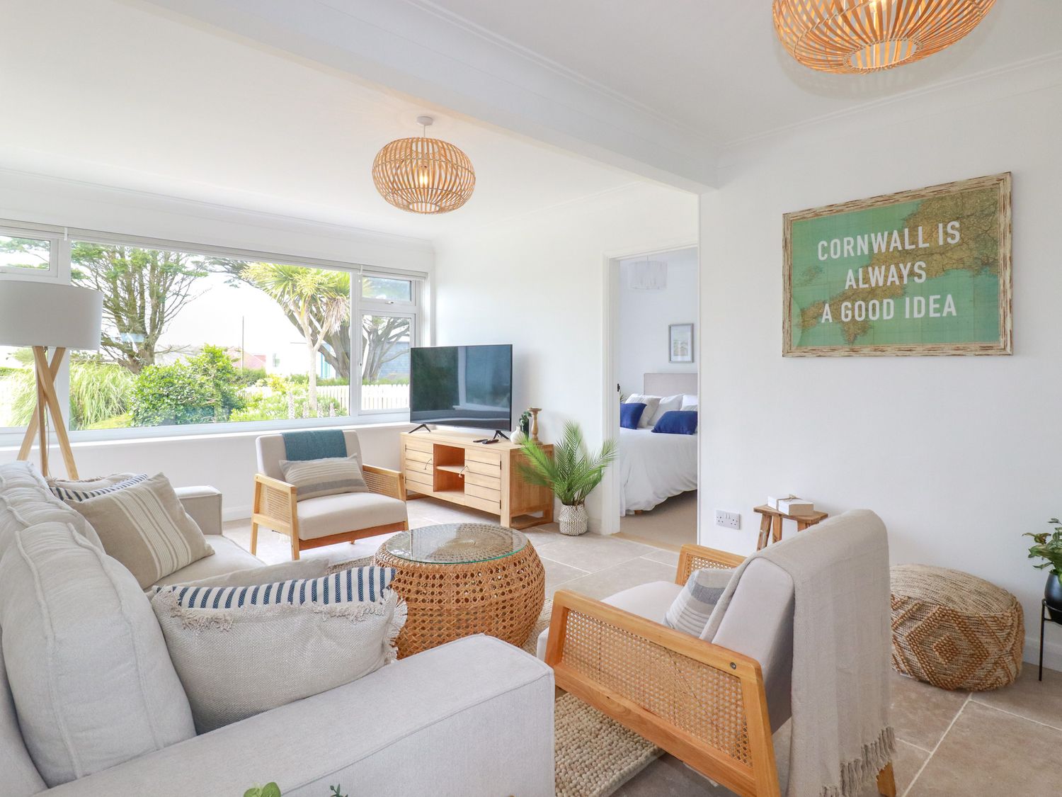 A living room with armchairs a sofa a television and a framed map on the wall at Polwen in Harlyn Bay Padstow