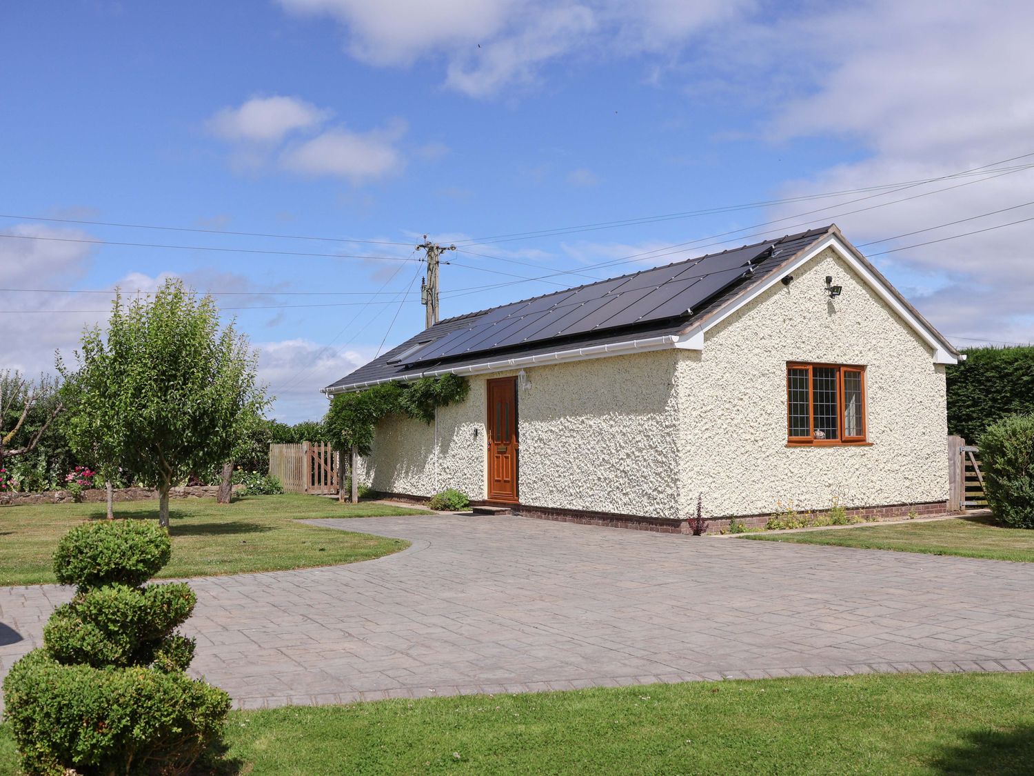 A house with a driveway and garden at The Brambles in Holt, North Wales