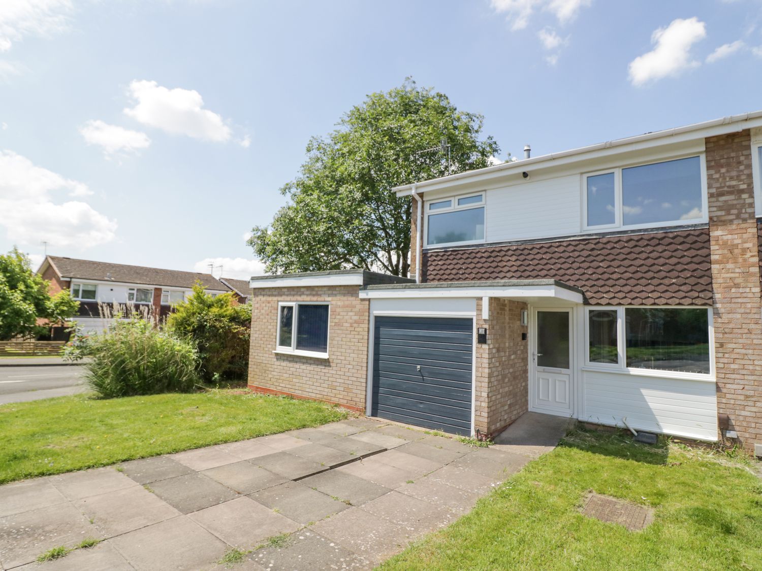 A two-story house with a garage and driveway and lawn at Shirleys in Stratford-Upon-Avon