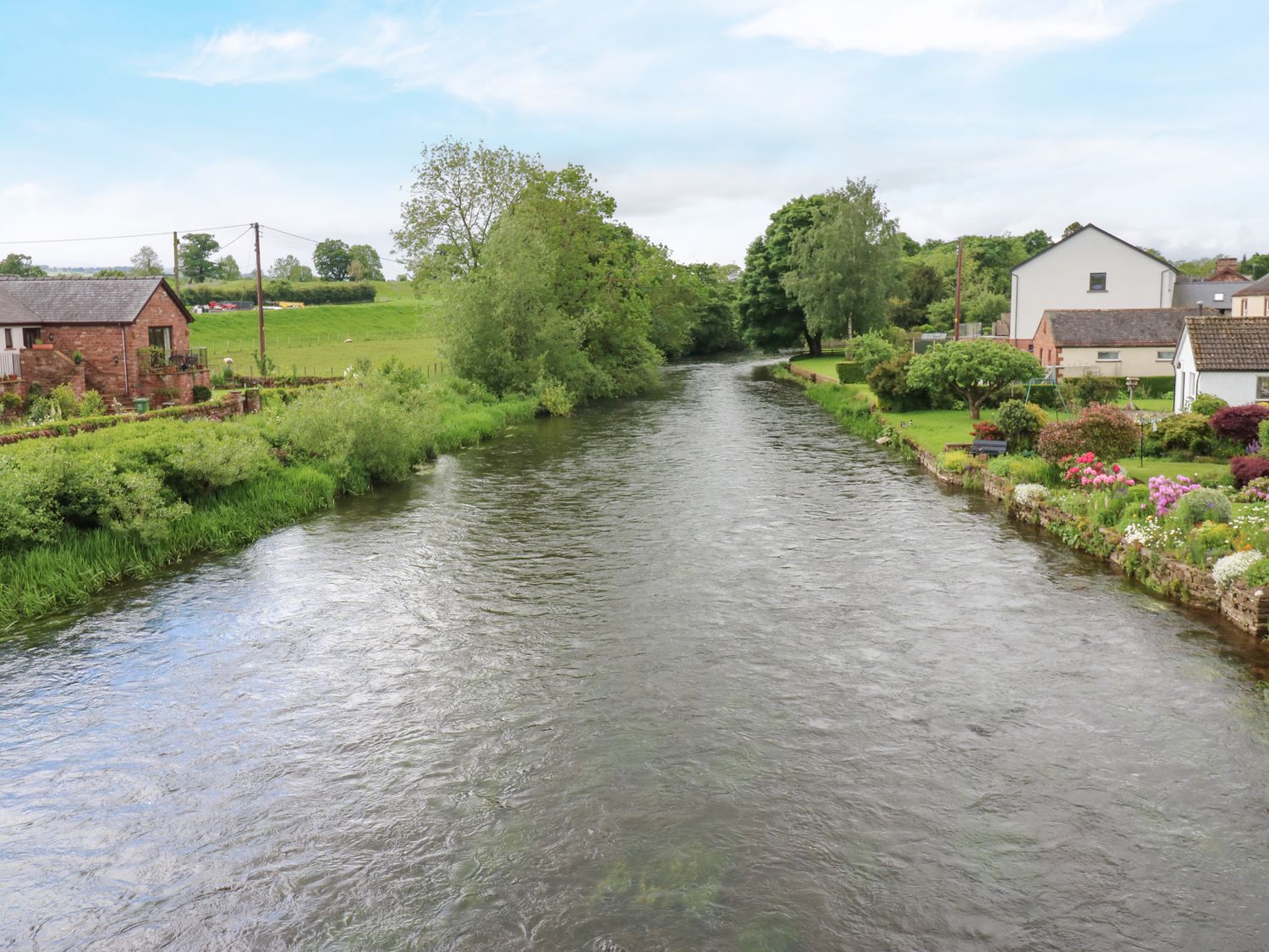 A river with trees and houses on either side at River Cottage in Eamont Bridge