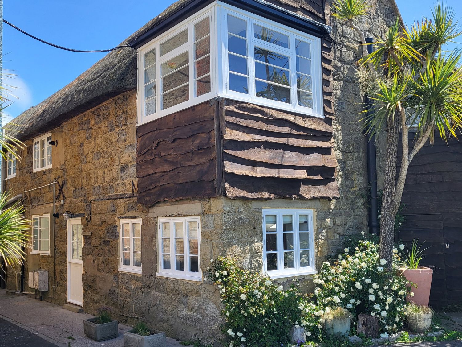 An exterior view of a cottage with a thatched roof and wooden panels at Fishermans Locker, West Bay