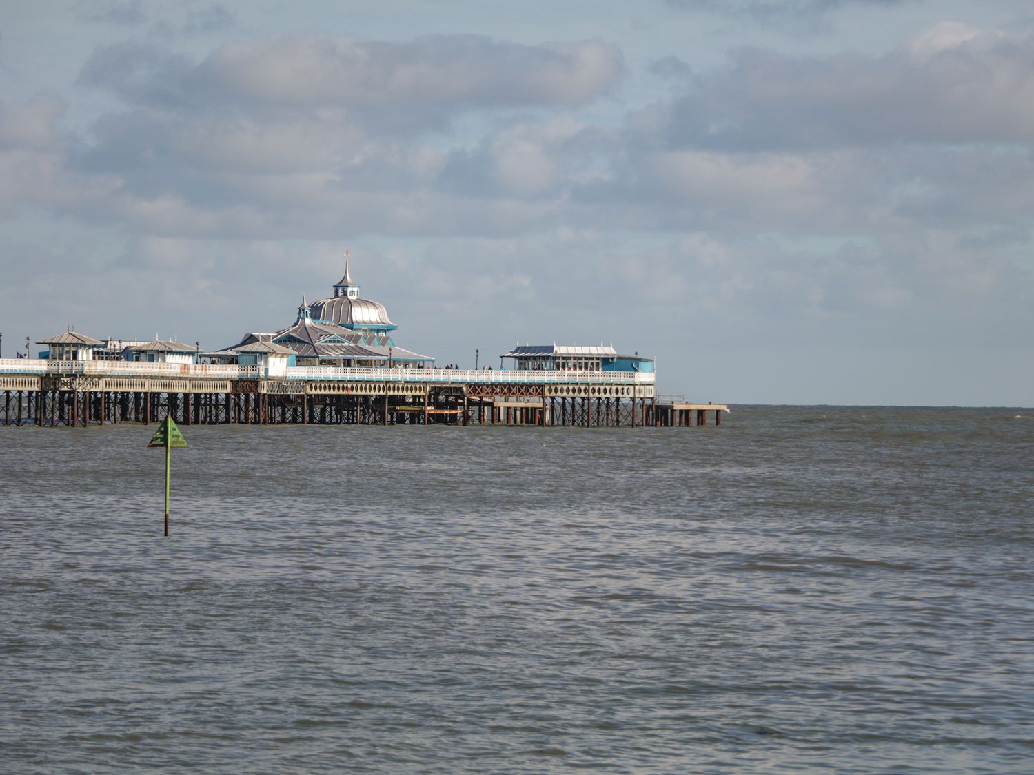 A pier extending into the sea under a cloudy sky