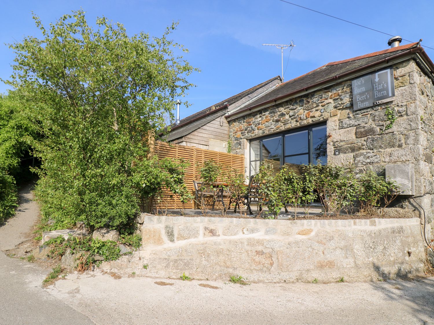 A barn with outdoor seating and plants at Joe's Barn in Mullion