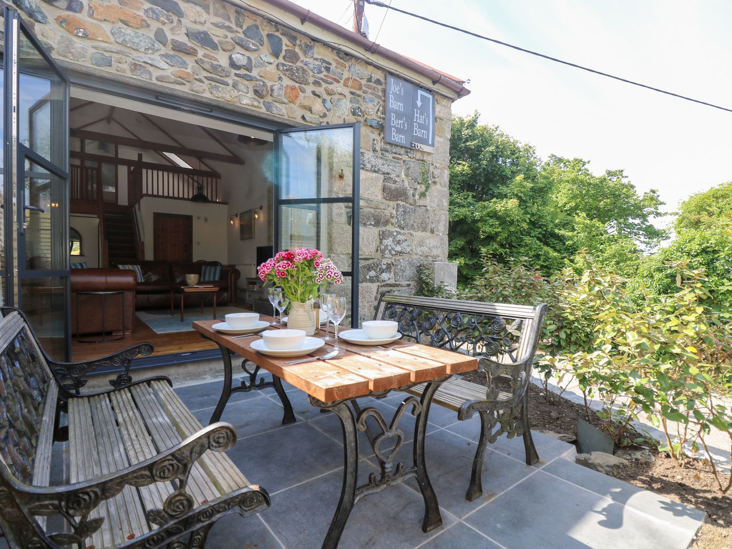 An outdoor seating area with a table and benches at Joe’s Barn in Mullion