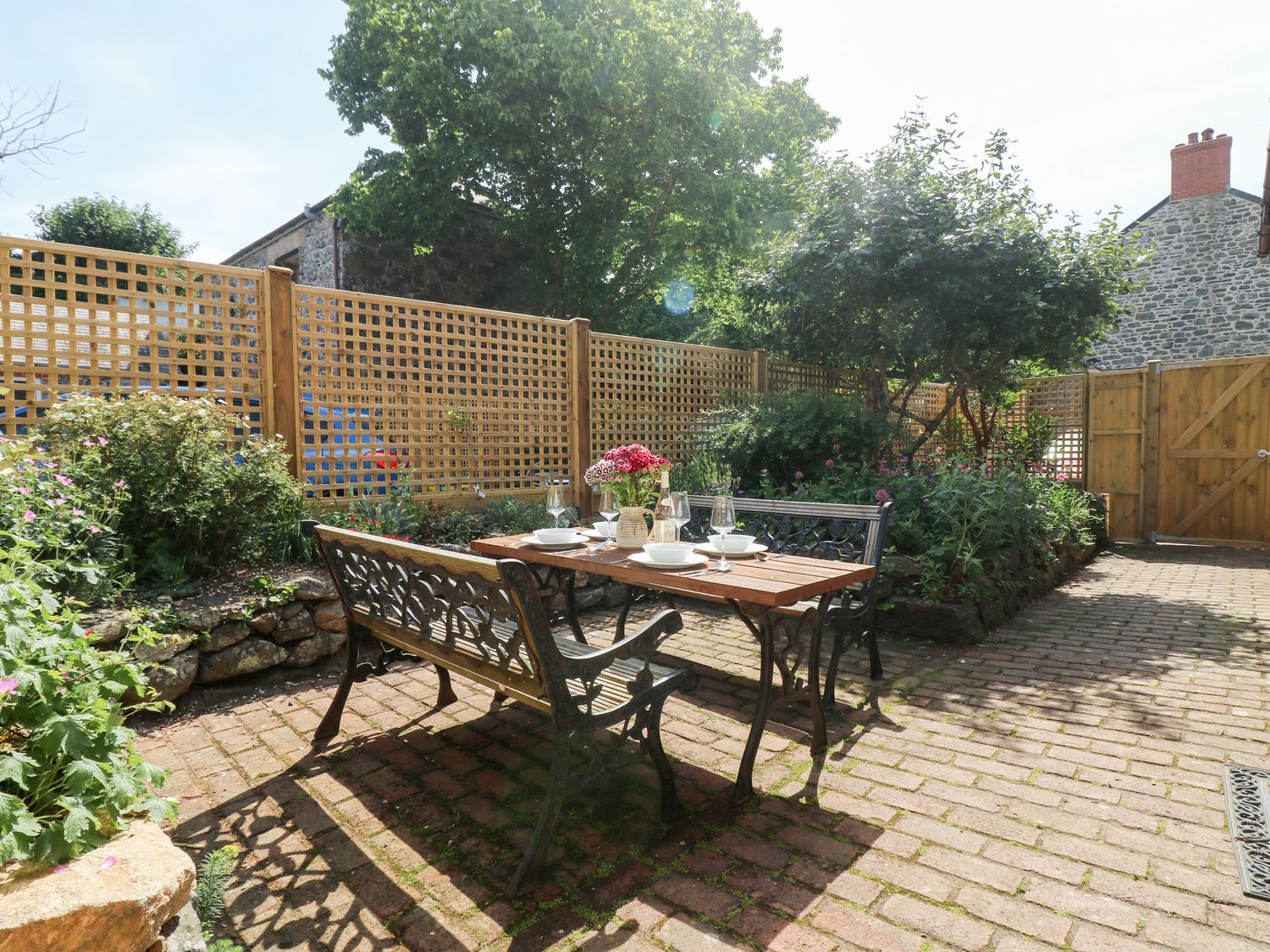 A garden with a table and chairs surrounded by plants at Bert's Barn, Mullion