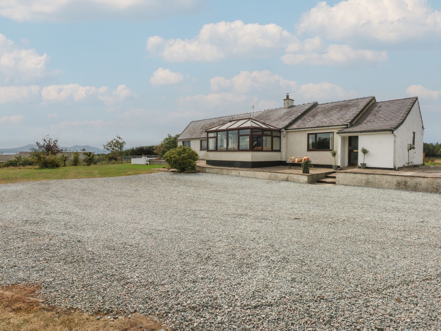 A house with a gravel area and plants at Tir Mawr in Llanfairpwllgwyngyll