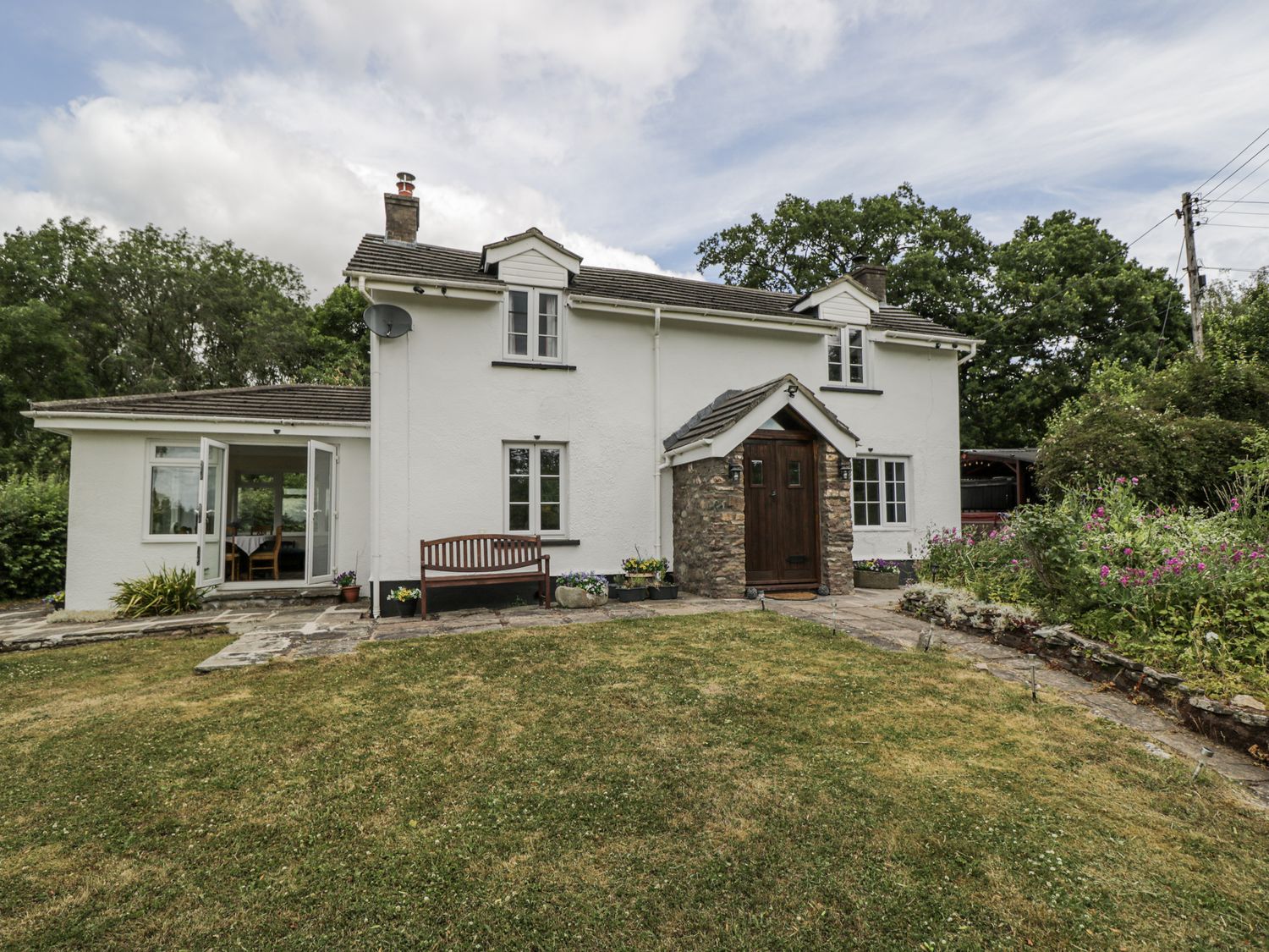 A house with a garden and patio at Woods Cottage Kingcoed near Raglan