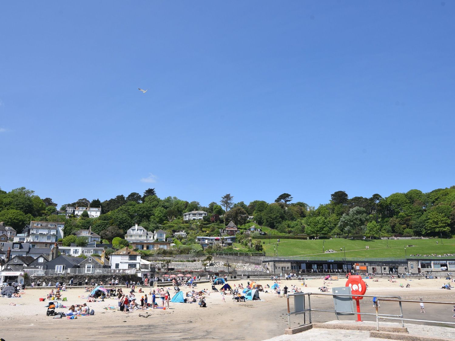 A sandy beach with people and small tents near houses and green hills at 16 Church Street in Lyme Regis