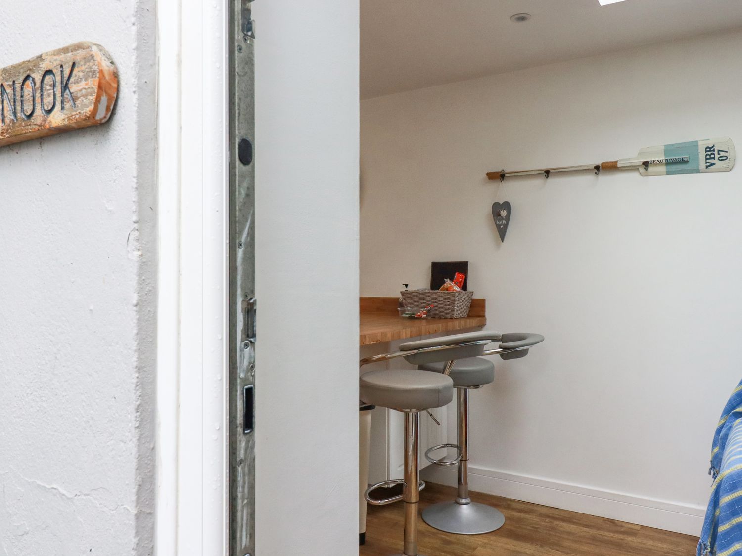 A small dining area with a wooden countertop and two bar stools with gray seats at The Nook in Newquay