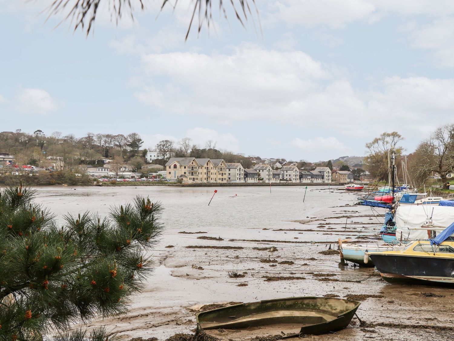 A riverside with boats on muddy banks and buildings in the background at The Heights in Truro