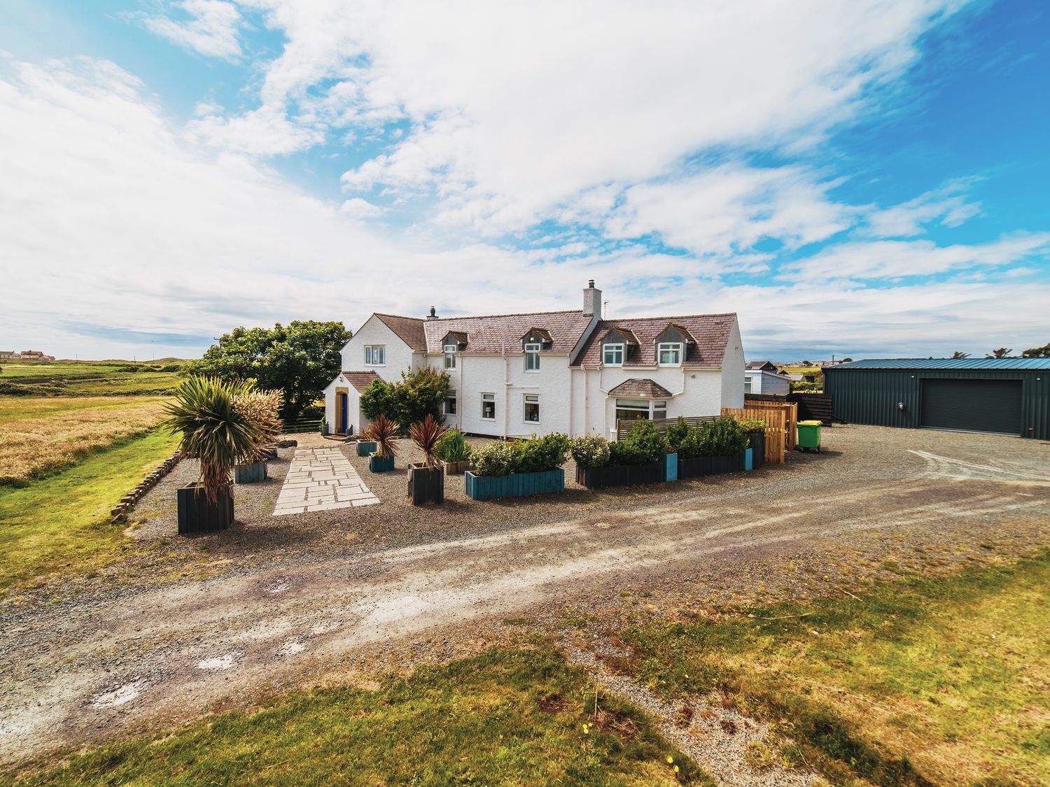 An outdoor view of a house with garden and garage at Glanllyn Bach Llanfaelog