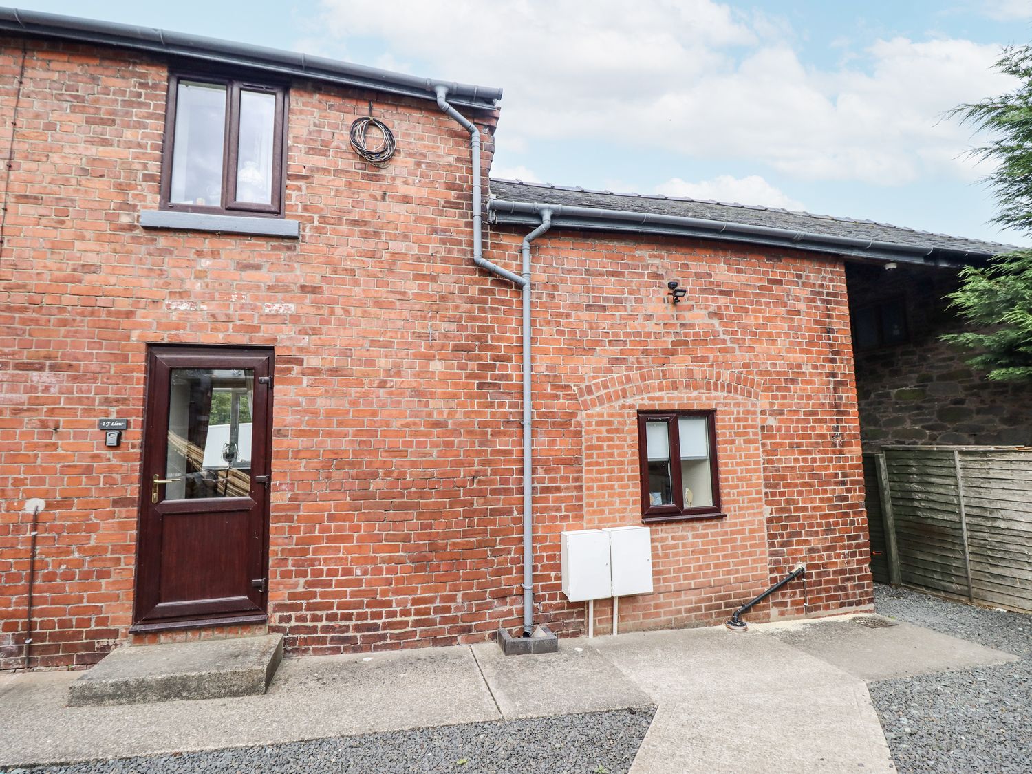 An exterior view of a brick building with a door and windows at 1 Y Llew in Llandinam