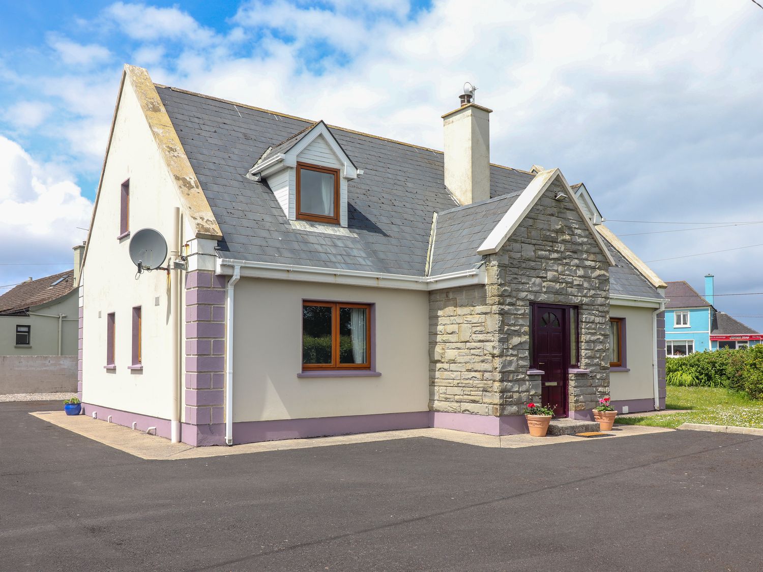 A stone and plaster house with a dark front door and purple window frames at Levally House in Mountrivers Bridge near Doonbeg County Clare