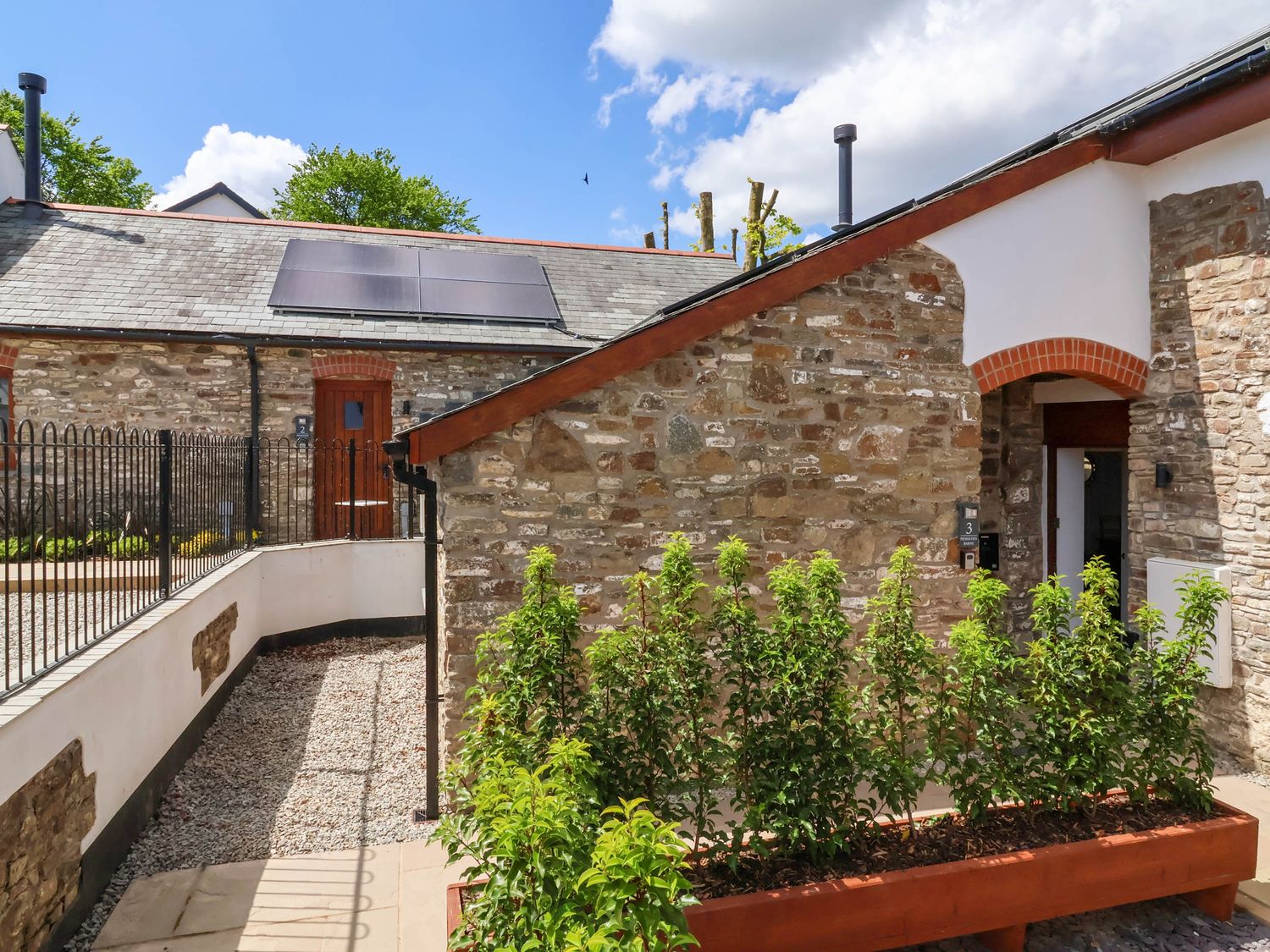 A courtyard with stone buildings and plants in a planter at Ladybird Rest in Parkham near Bideford
