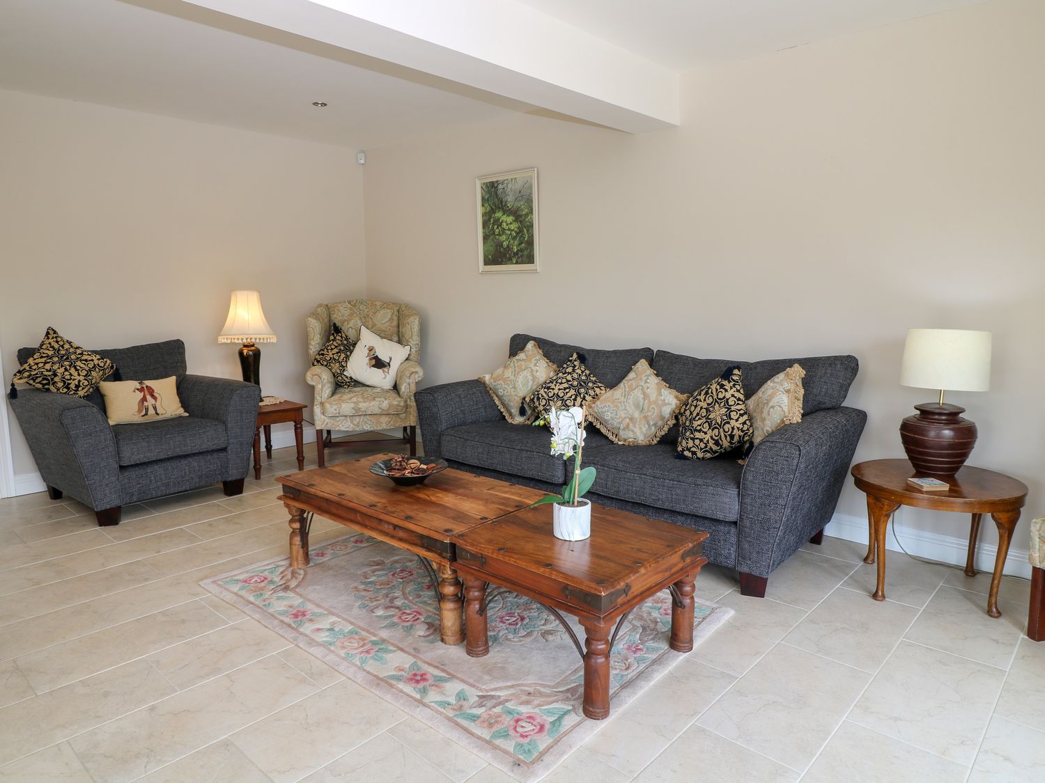 A living room with grey sofas a wooden coffee table and lamps at Monument View in Hawkesbury Upton