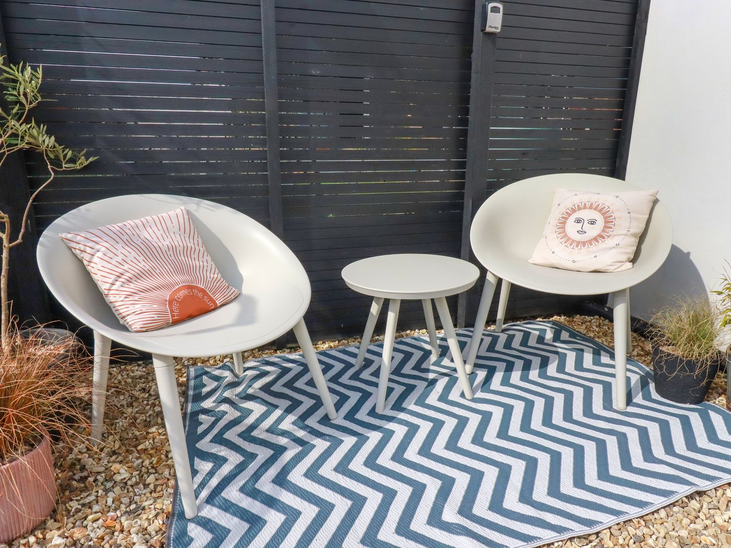 An outdoor seating area with two chairs a small round table and a chevron patterned rug at Gwynn lodge in Newquay