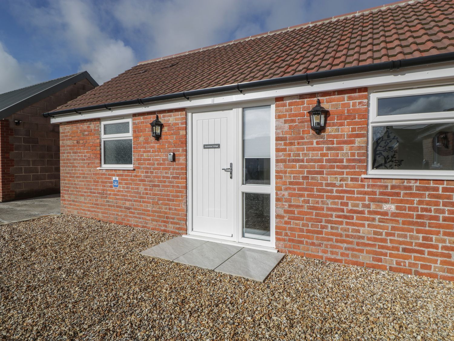 Exterior view of a brick cottage with a white door and two windows at Doubletree Cottage in Swainsford near Mere