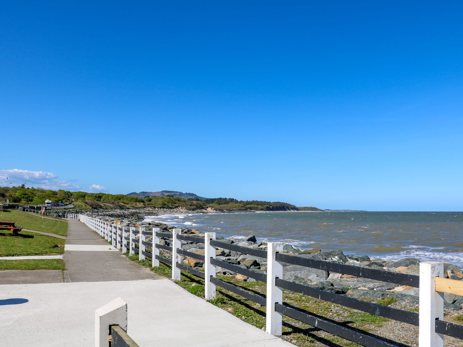 A coastal walkway with a wooden fence along the rocky shore and grassy area near Stargazer in Tara Hill near Ballymoney County Wexford