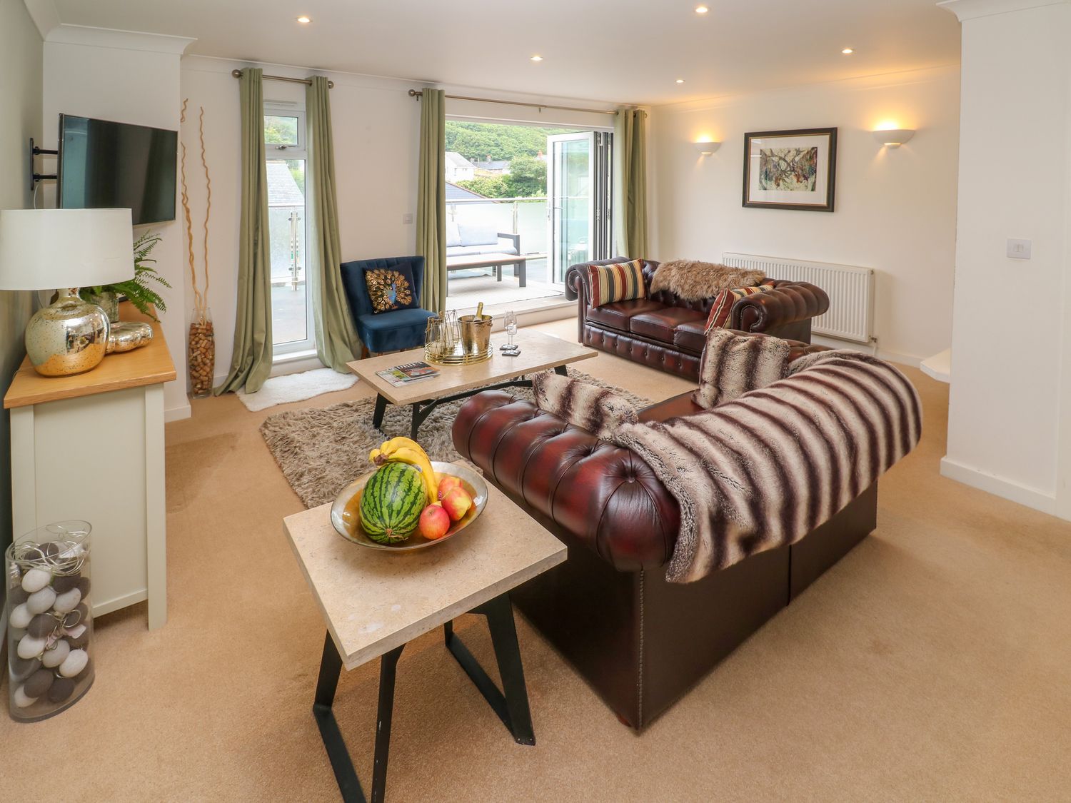 A living room with leather sofas a blue chair and a coffee table at Apartment above Garryglass in Portreath