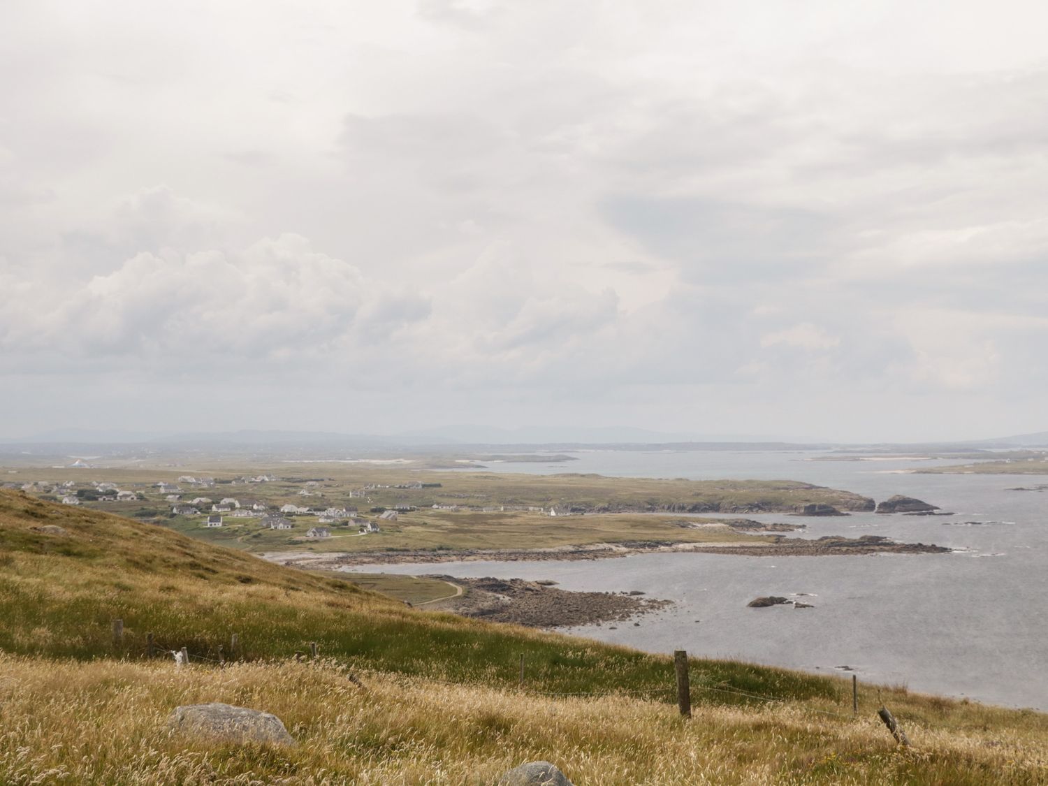 A coastal landscape with grass-covered hills and scattered houses near the shore at The Island's View in Gortahork County Donegal