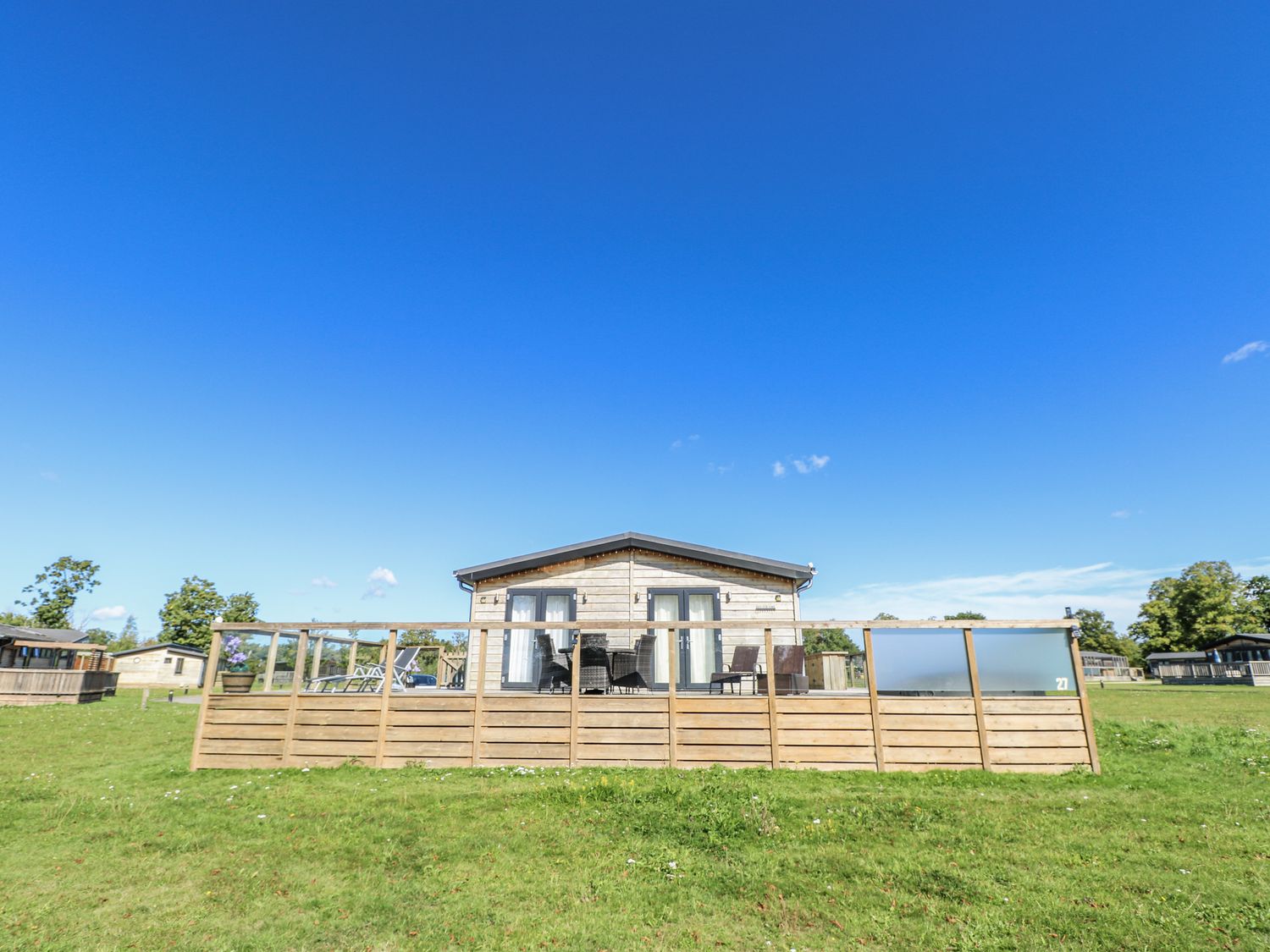 A cabin with a wooden deck and outdoor furniture at Angel Lodge - No 27, Fornham St Genevieve near Bury St Edmunds
