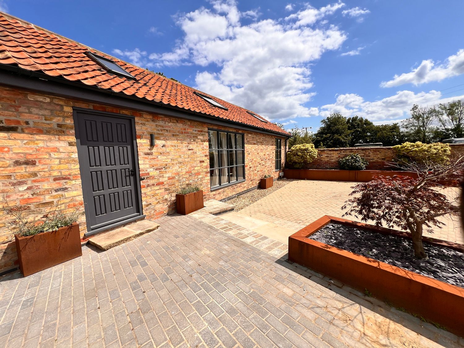 An outdoor area with a brick wall and planters at Sabi in Gembling near Beeford