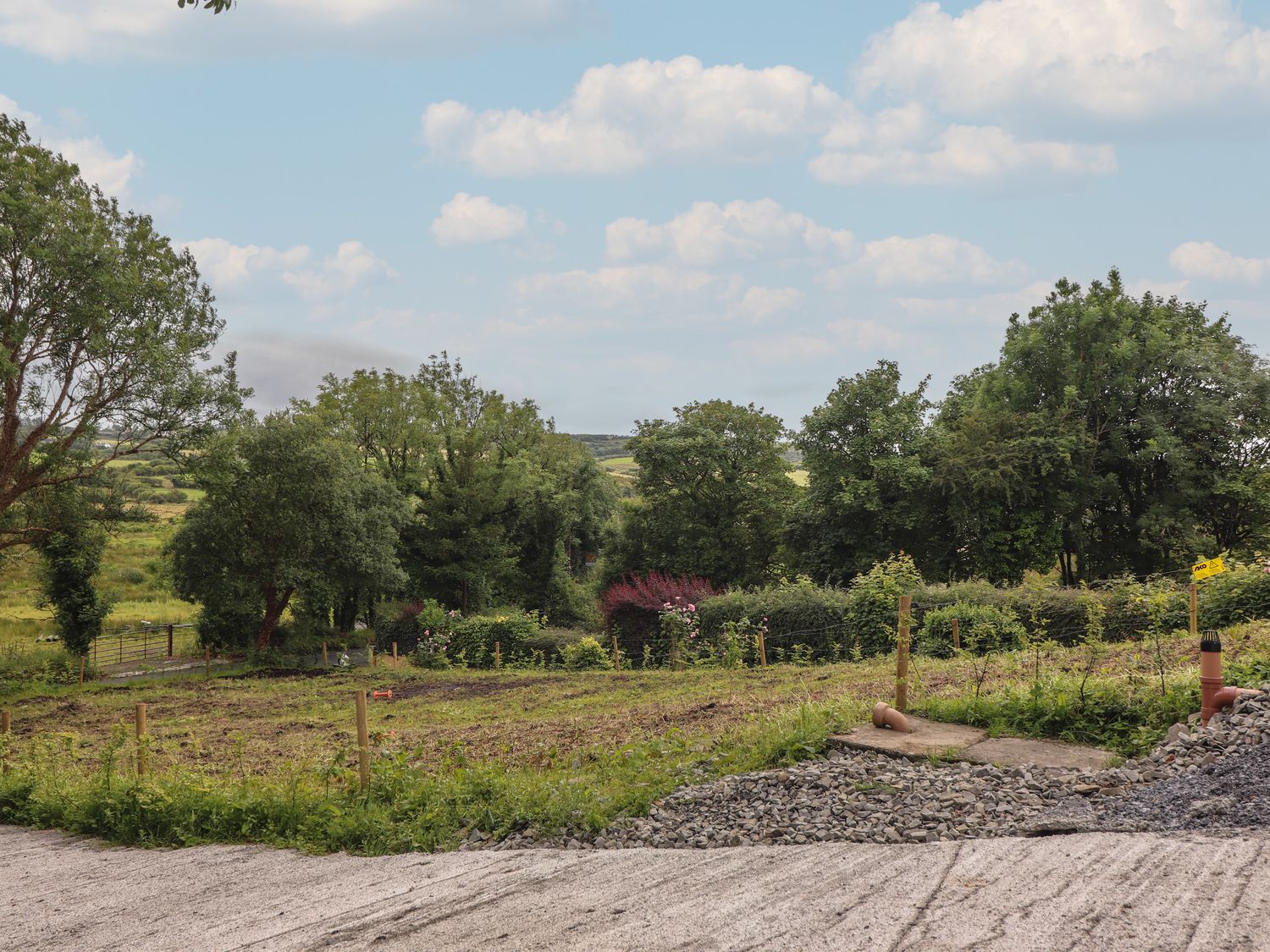 A rural field with fencing and trees under a partly cloudy sky at Hogans Cottage Cullenagh near Ennistymon County Clare