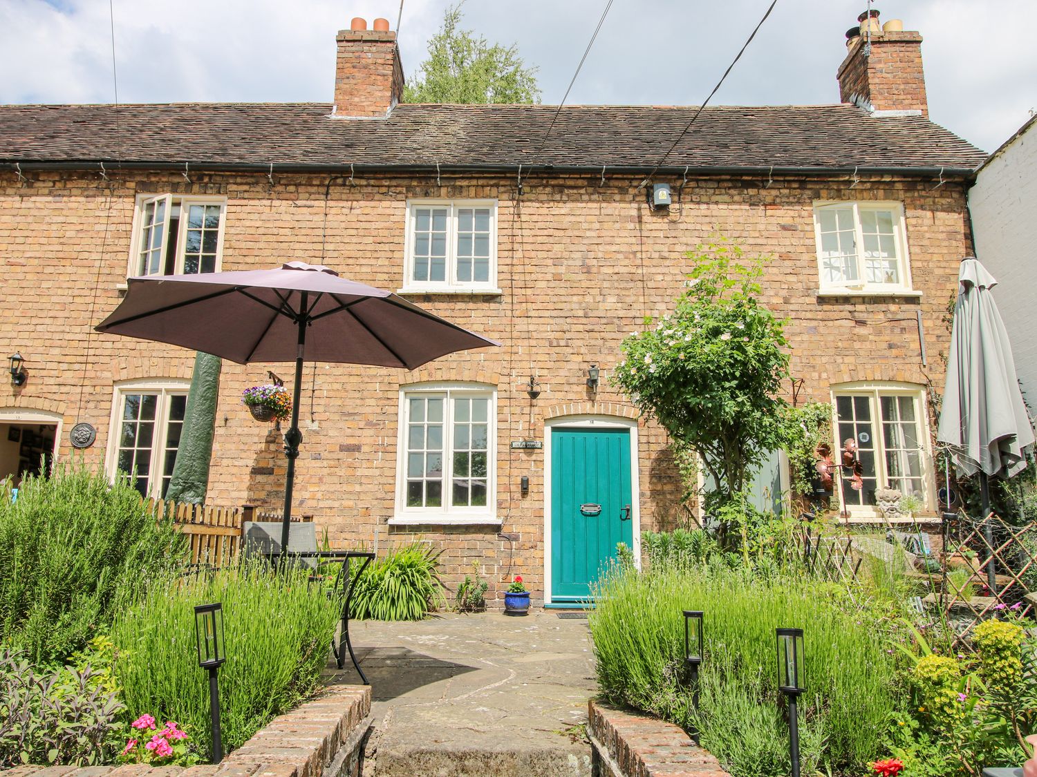 A cottage facade with a garden and umbrella at Medlar Cottage Ironbridge