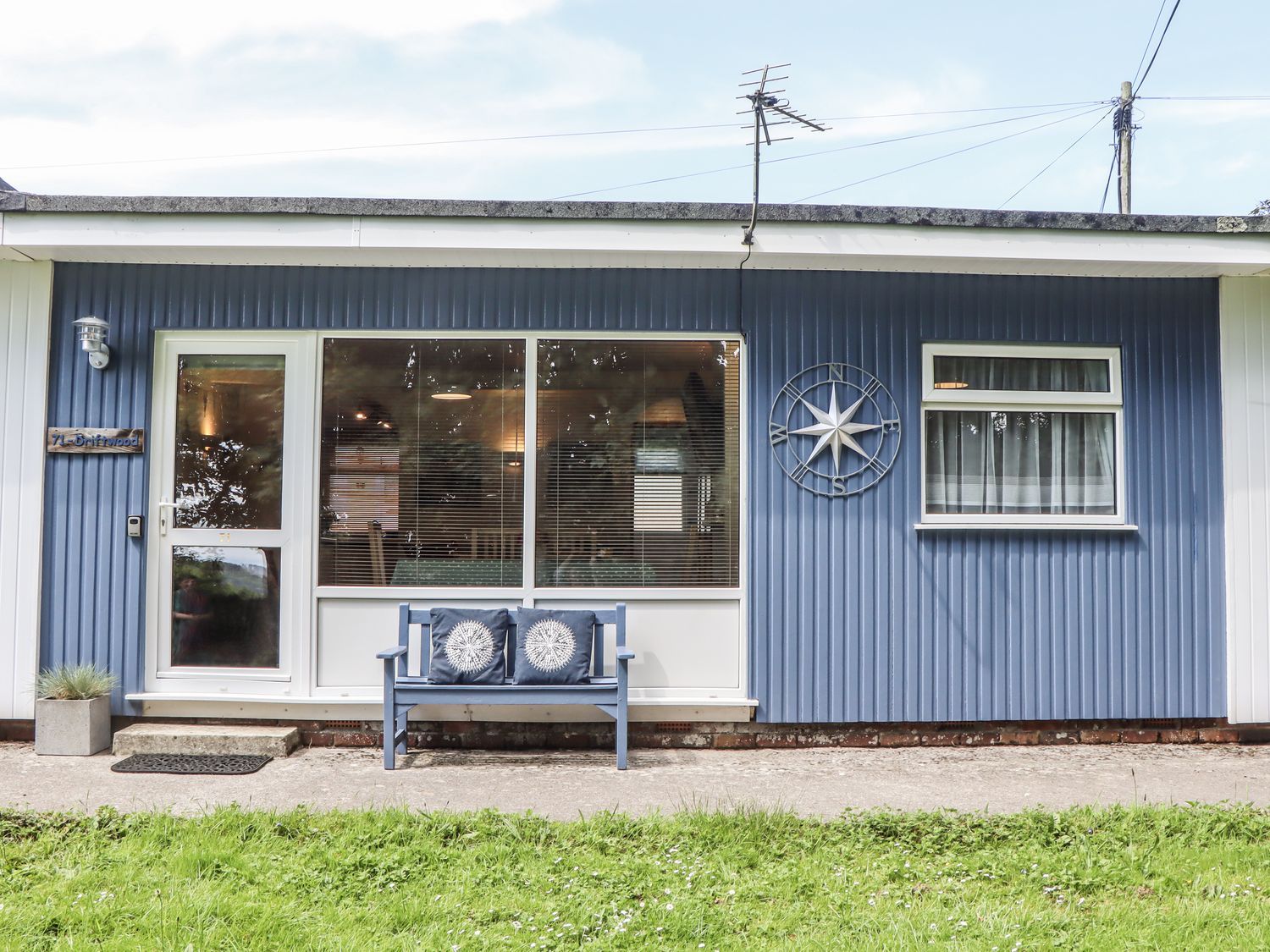 A house with a blue exterior and a bench at Driftwood in Dartmouth