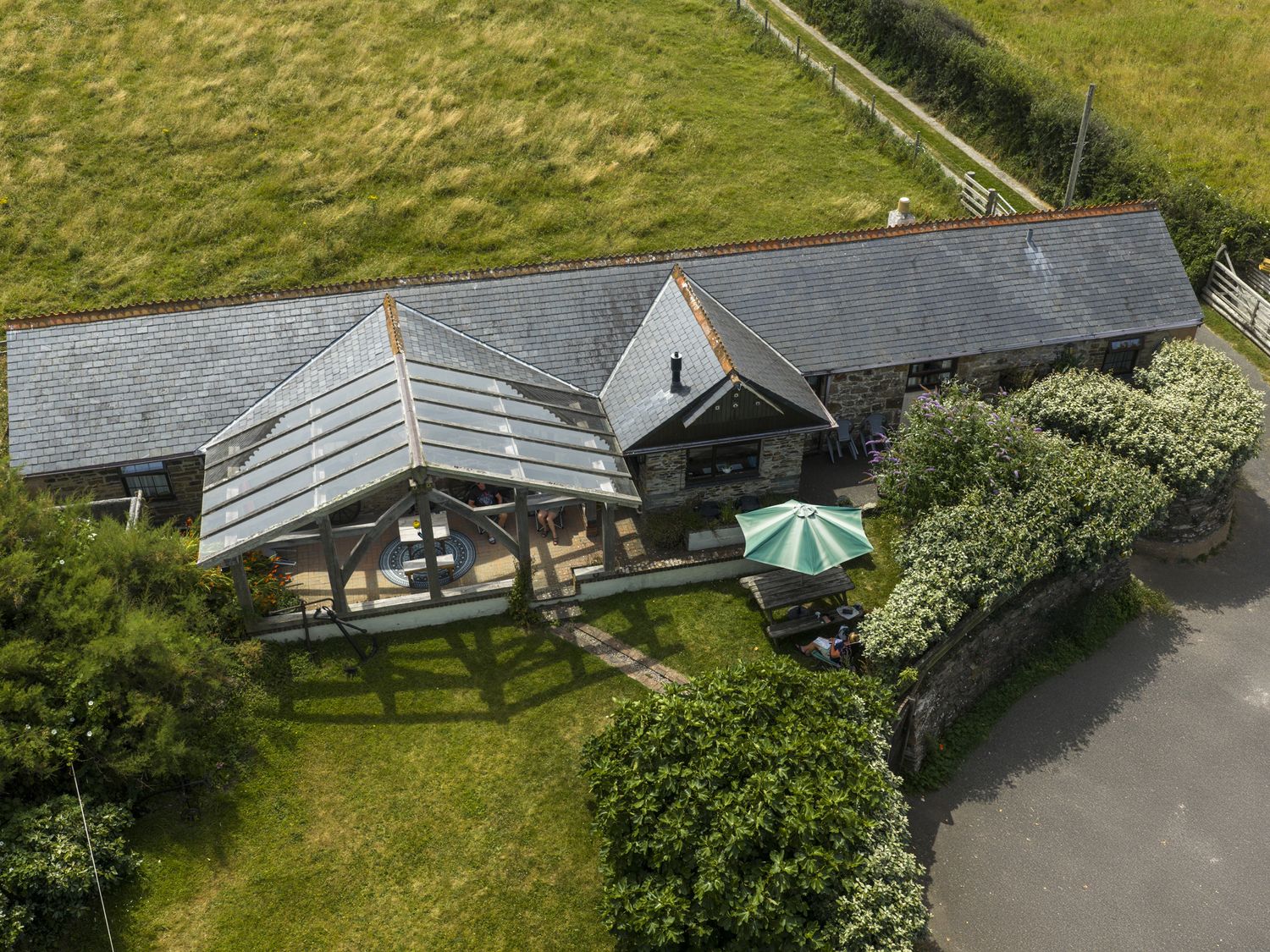 A patio with seating area and parasol at Horseshoe Cottage near Holywell Bay