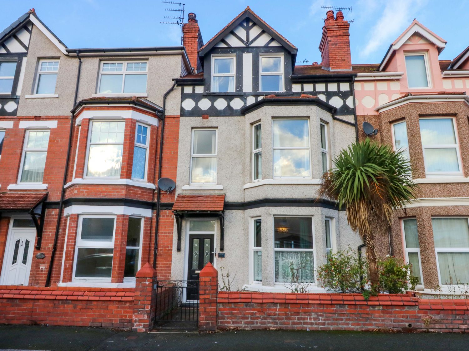 A house with multiple windows and a palm tree at Curzon Heights in Llandudno