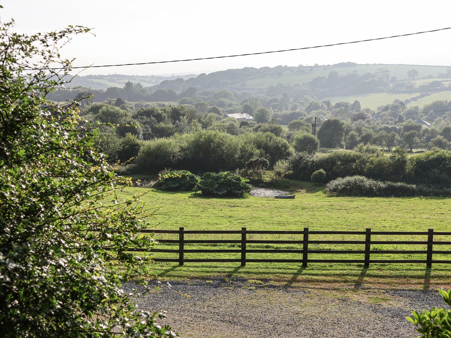A view of a grassy area with trees and hills at The Byre in Common Moor near Liskeard