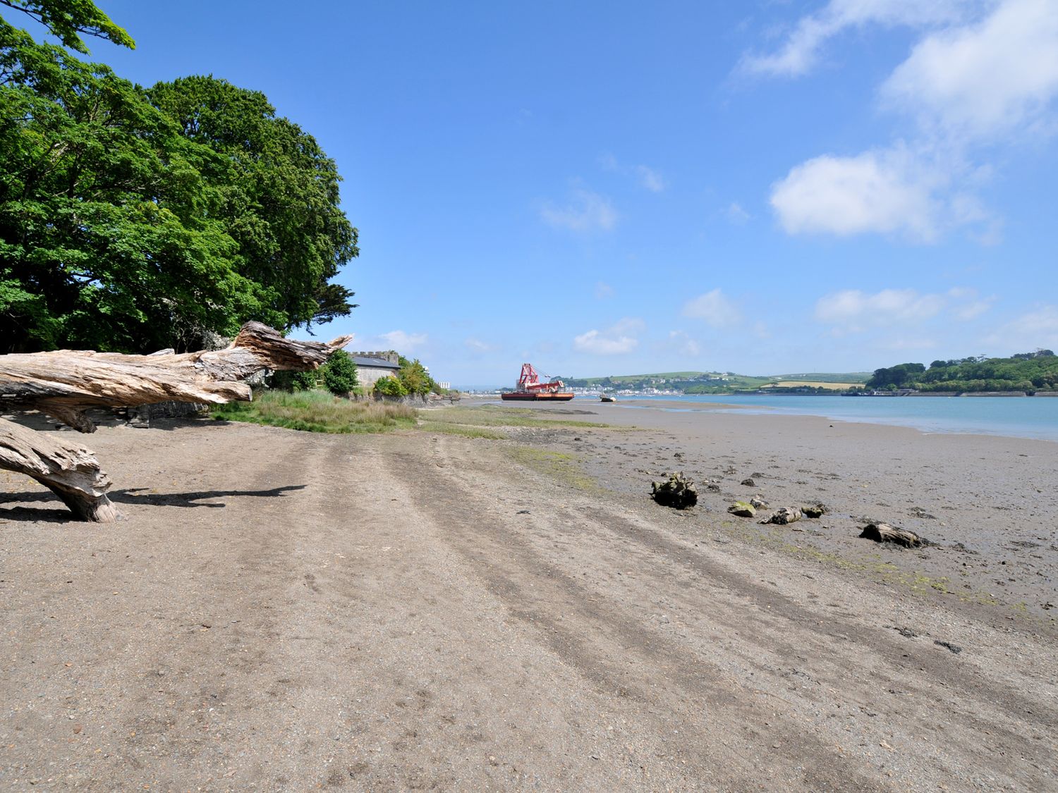 A view of a beach with driftwood and a boat at The Mooring in Northam