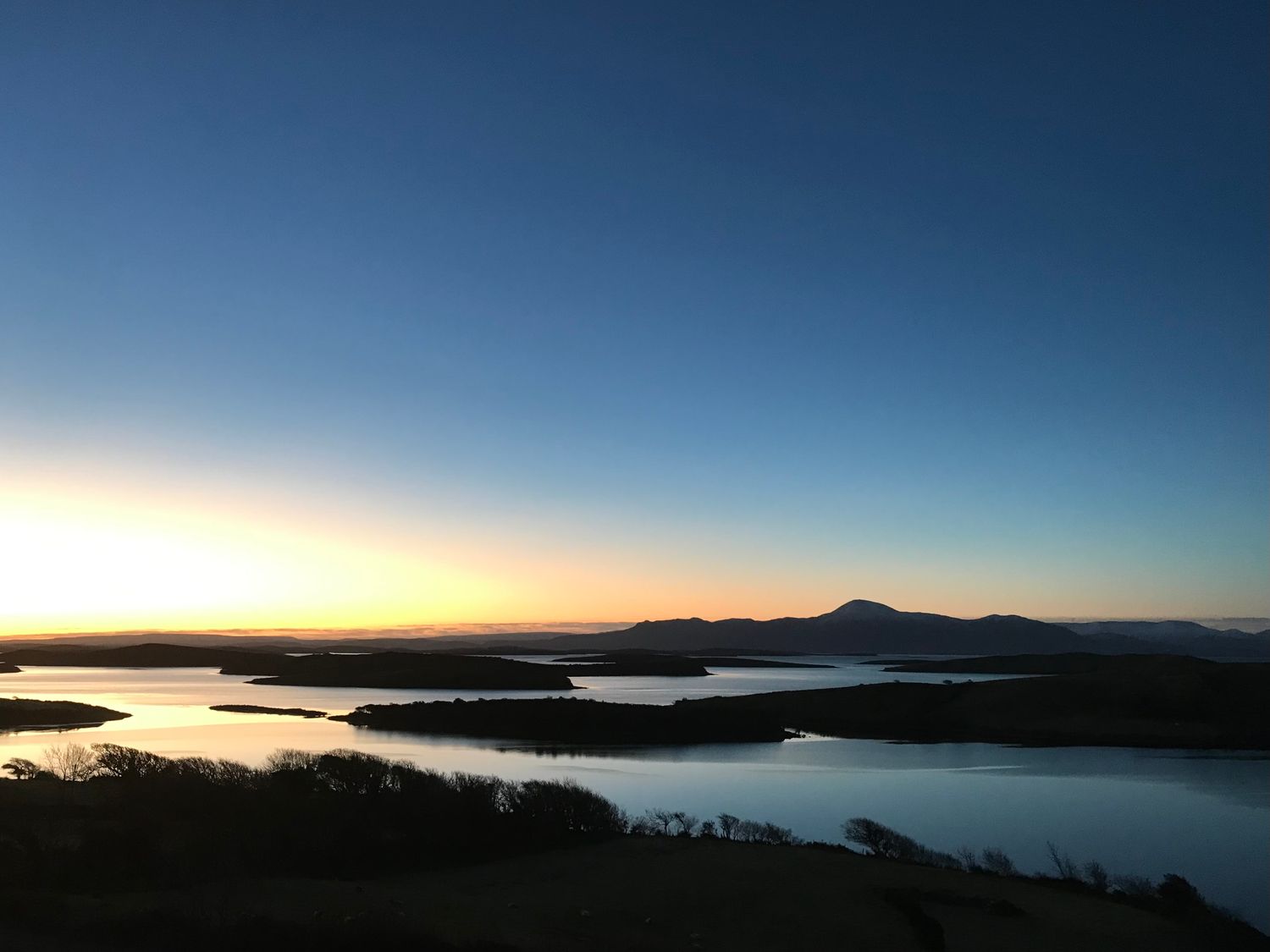 A landscape view of water and islands at sunset at Lighthouse Hill in Tiernaur near Mulranny