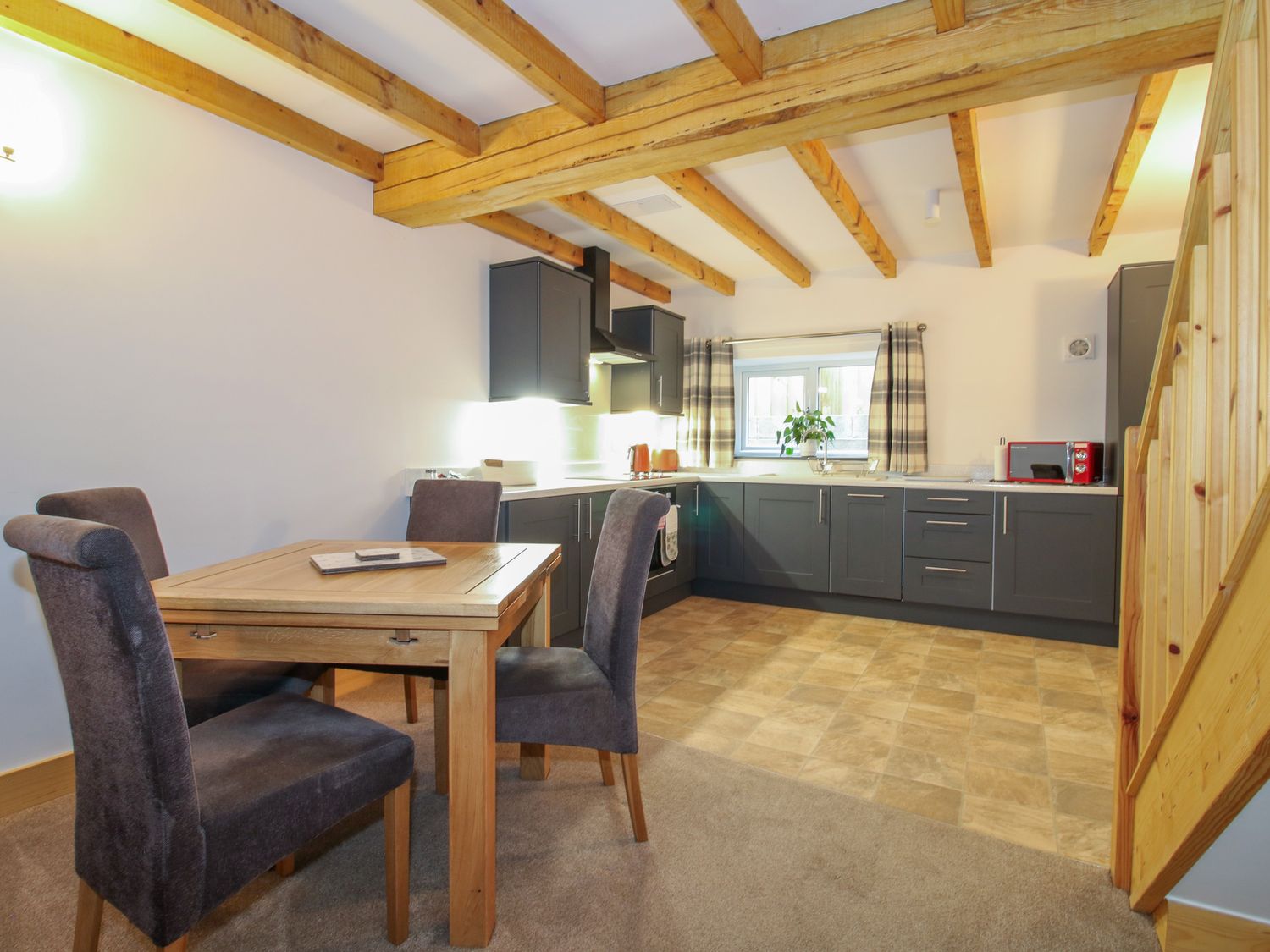 A kitchen and dining area with wooden beams on the ceiling and a wooden table with four chairs at Bangor in Knolton near Ellesmere