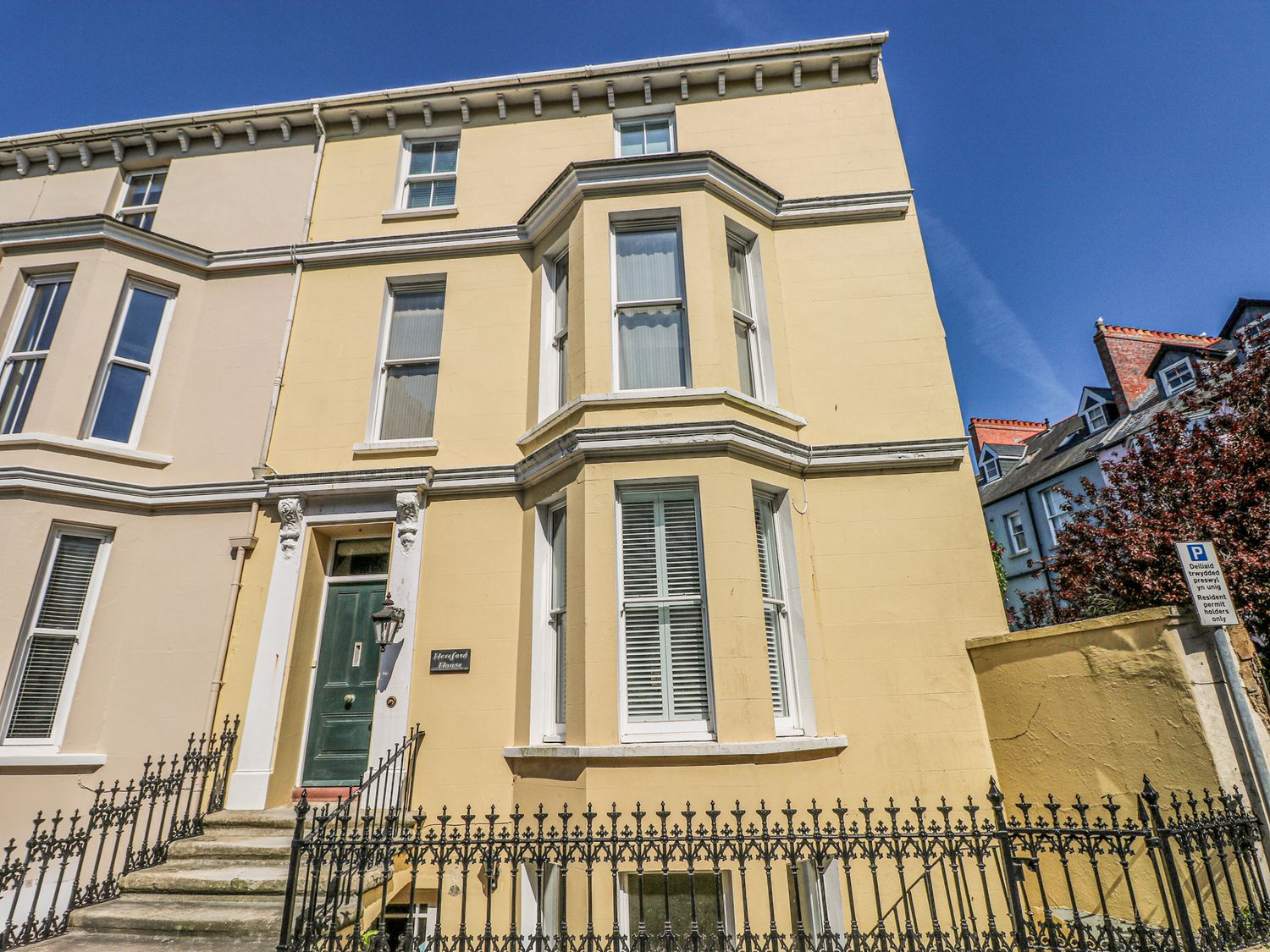 A yellow three-story house with a green door and white-trimmed windows at Hereford House in Tenby