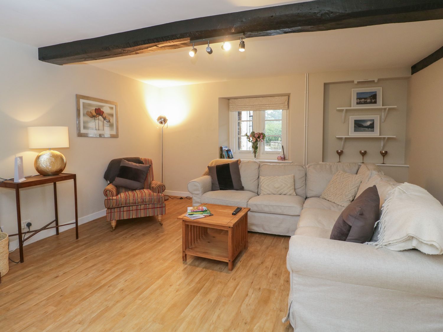 A living room with a beige sofa and striped armchair with a wooden coffee table at Little Wick in Lacock