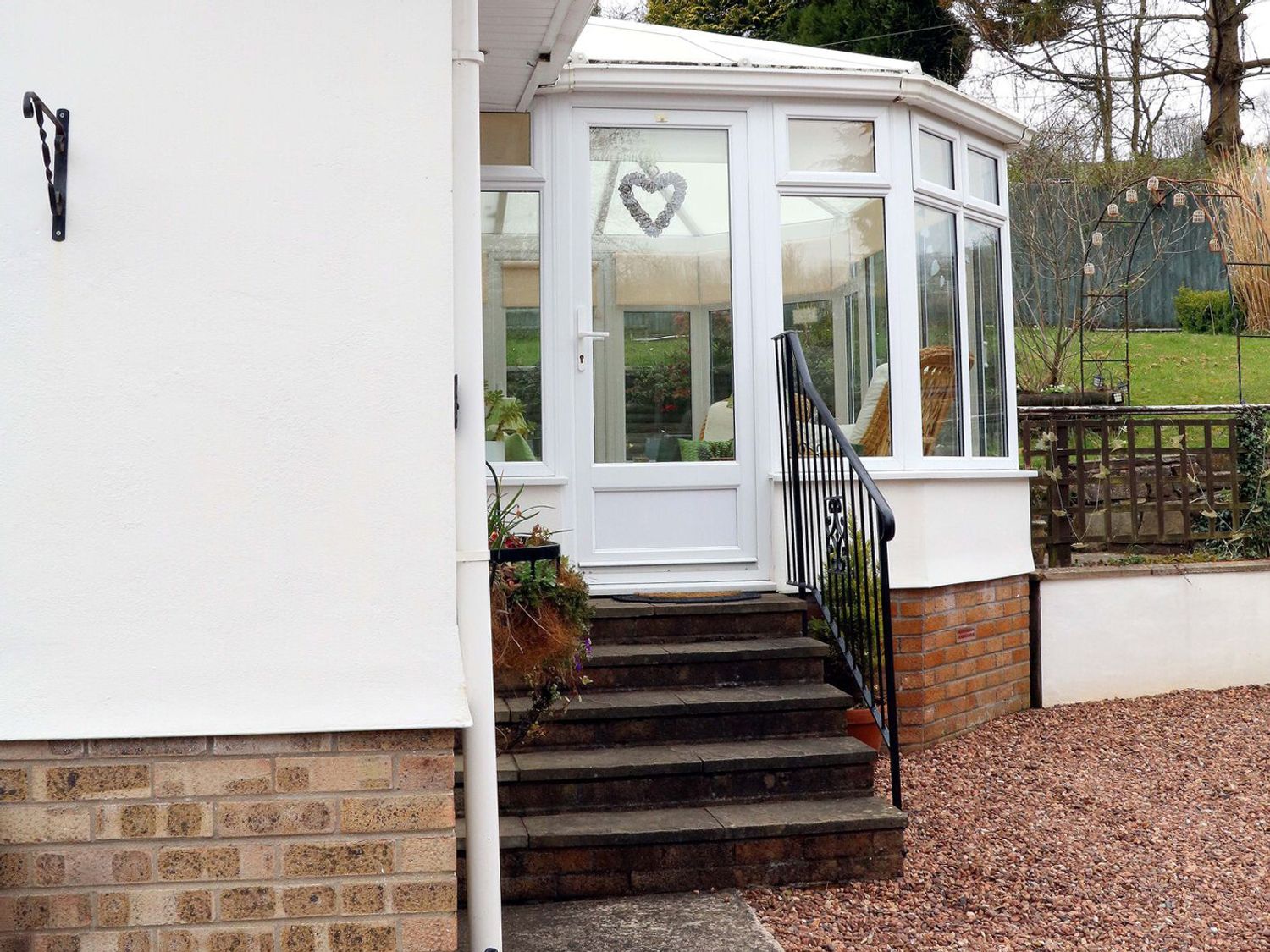 Steps leading to a white conservatory with glass windows and a door at Little Willesleigh in Goodleigh near Barnstaple