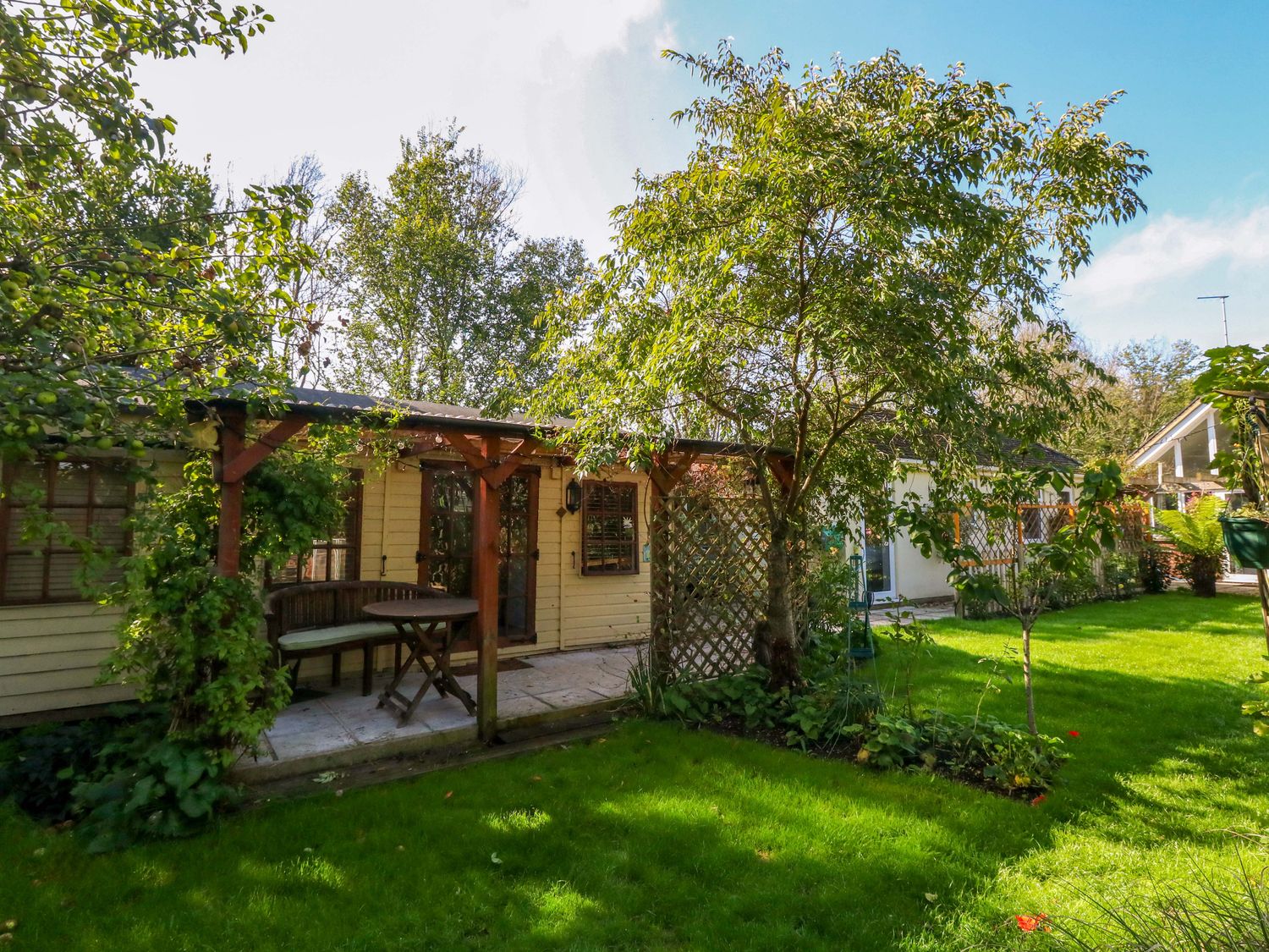 A garden with a shed, table, and trees at The Cabin at Little Timbers Ringwood